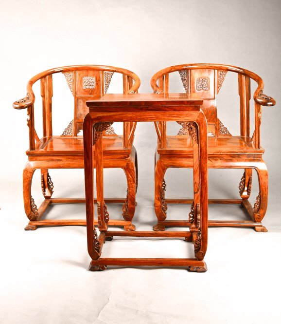 Chinese Carved Huanghuali wood chairs and a tea table: A pair of ornately carved Huanghuali wood armchairs with a horseshoe shaped back, pierced conforming splat, box stretchers and satin cushions; oah, and a Huanghuali wood teatable. Chair size, Height 3