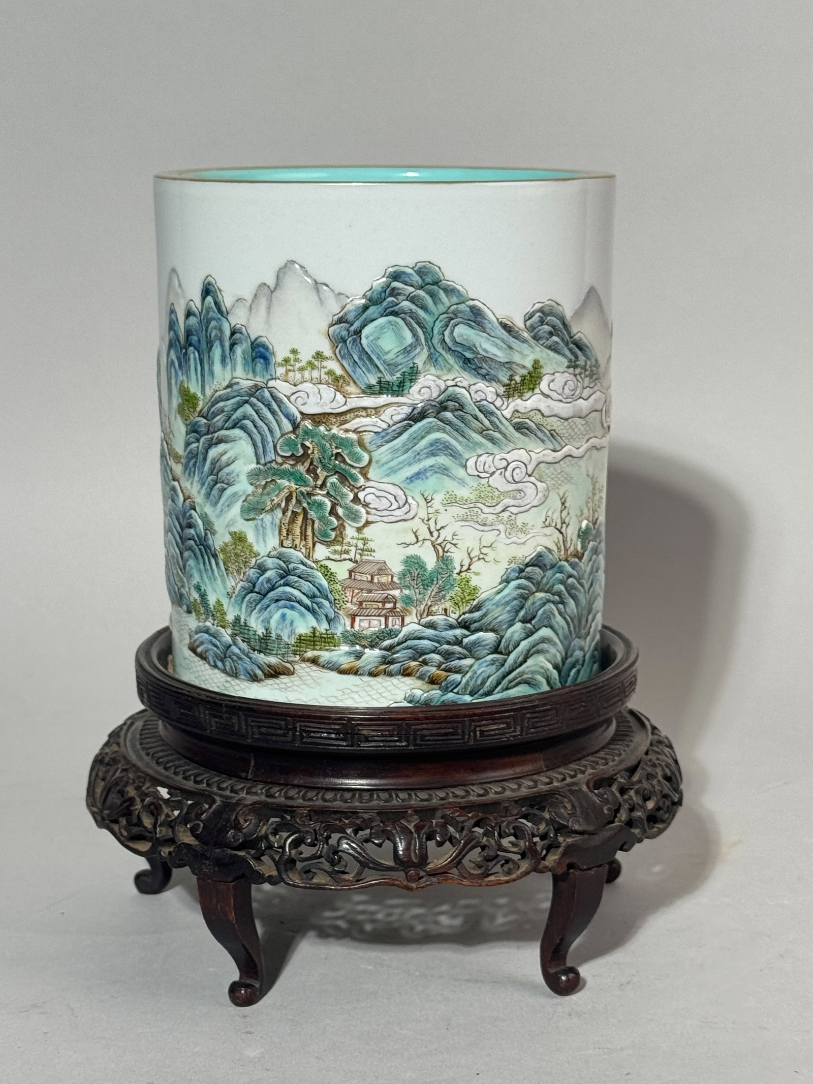 A CHINESE PORCELAIN BRUSHPOT WITH LANDSCAPE SCENE: A Chinese porcelain brushpot with a moriage landscape scene, resting on a hardwood base. Dimensions: Diameter: 4.75 in. (12.1 cm); Height: 5.25 in. (13.3 cm). Note: This item is in New York, where it 