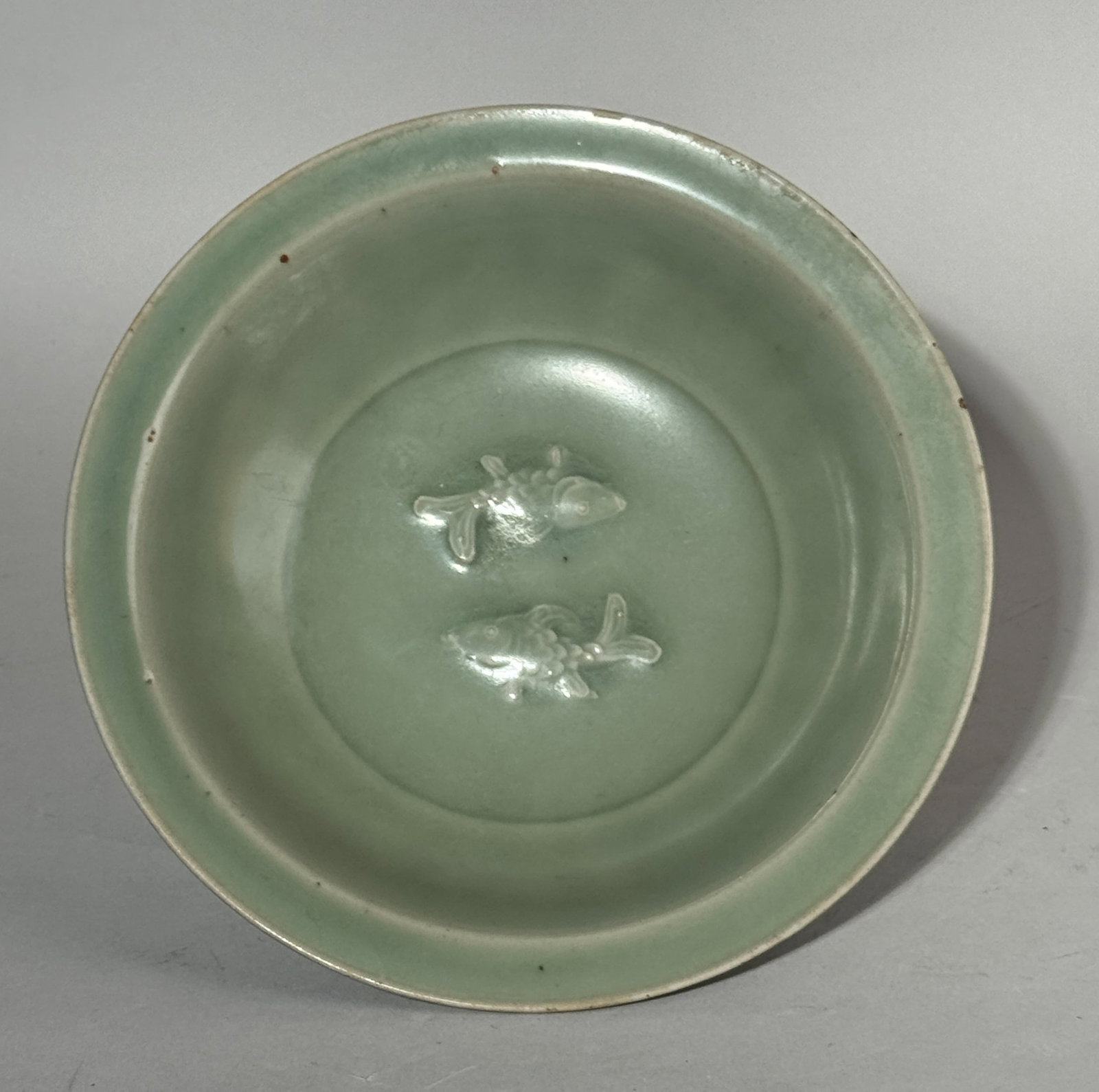A CHINESE MING CELADON PORCELAIN CHARGER WITH MORIAGE FISH: A Chinese Ming dynasty celadon porcelain charger with a moriage fish design. Dimensions: Diameter: 8.5 in. (21.6 cm). Note: This item is in New York, where it can be shipped from.