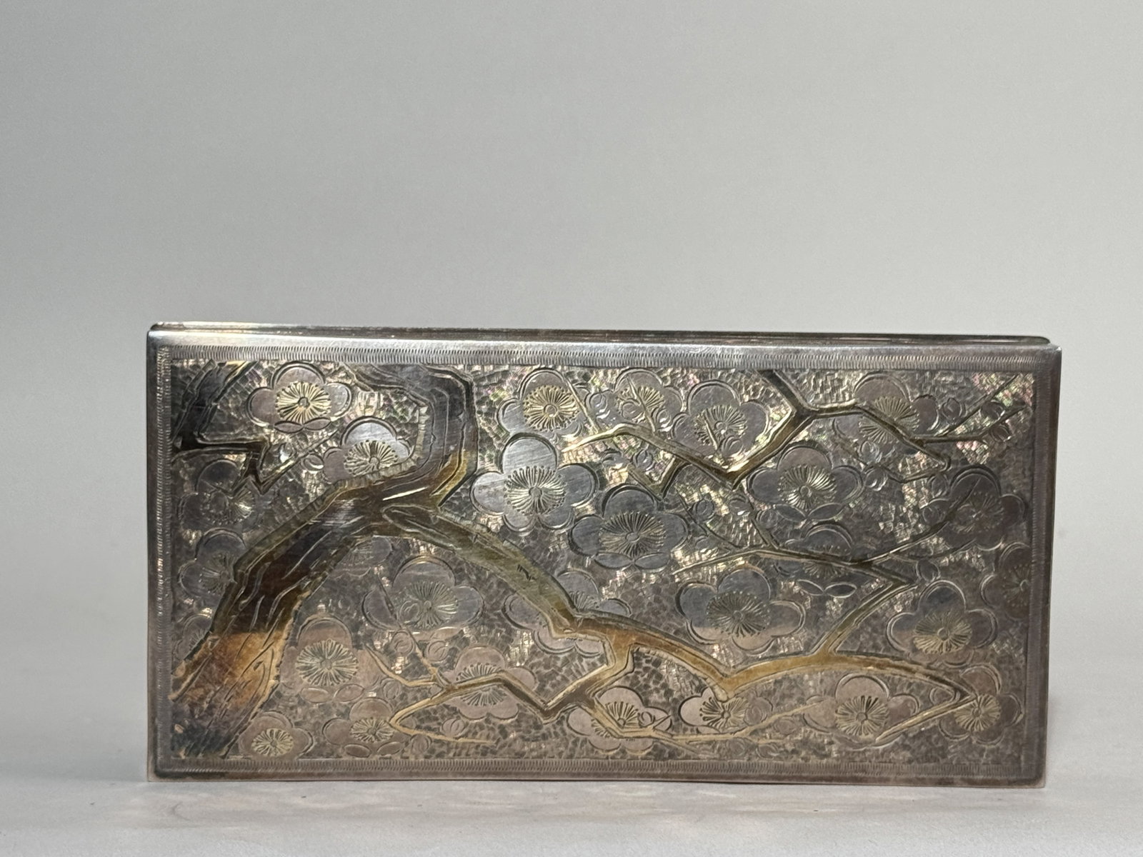 A JAPANESE SILVER BOX WITH PLUM BLOSSOM: An antique Japanese sterling silver box with a wood liner, decorated with plum blossoms. Gross weight 400 grams (12.86 ozt). Dimensions: Length: 7.25 in. (18.4 cm). Note: This item is in New York,