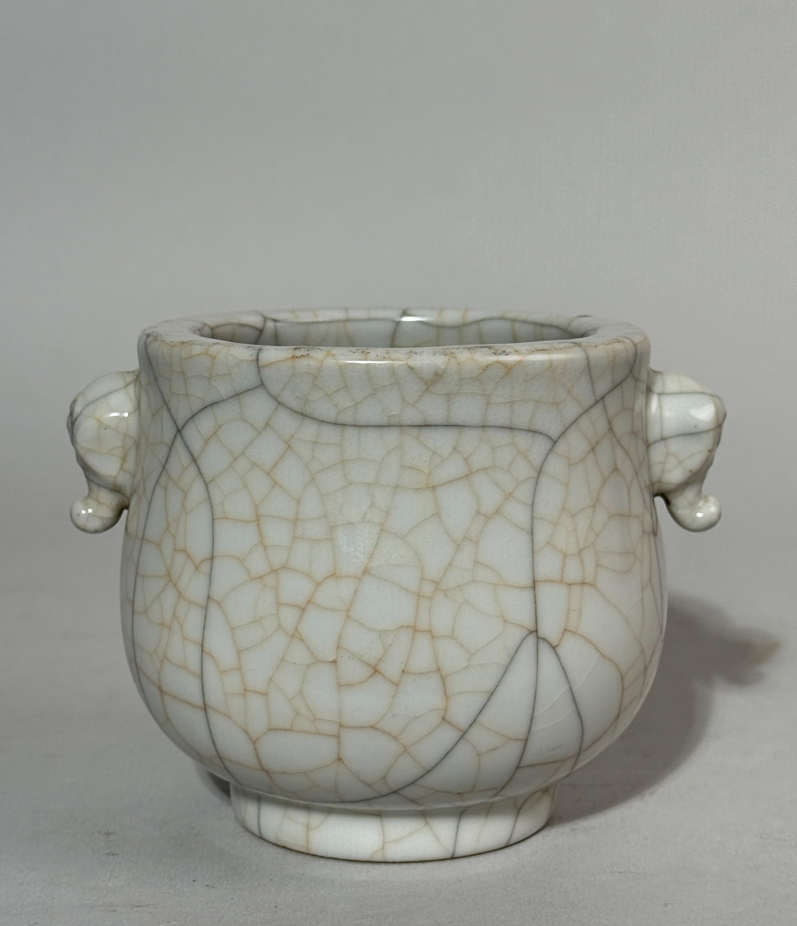 CHINESE GUAN CRACKLE PORCELAIN CENSER WITH ELEPHANT EAR HANDLE: A Chinese Guan crackle porcelain censer with elephant ear handles. Dimensions: Width: 4.5 in. (11.4 cm); Height: 3.5 in. (8.9 cm). Note: This item is in New York, where it can be shipped from.