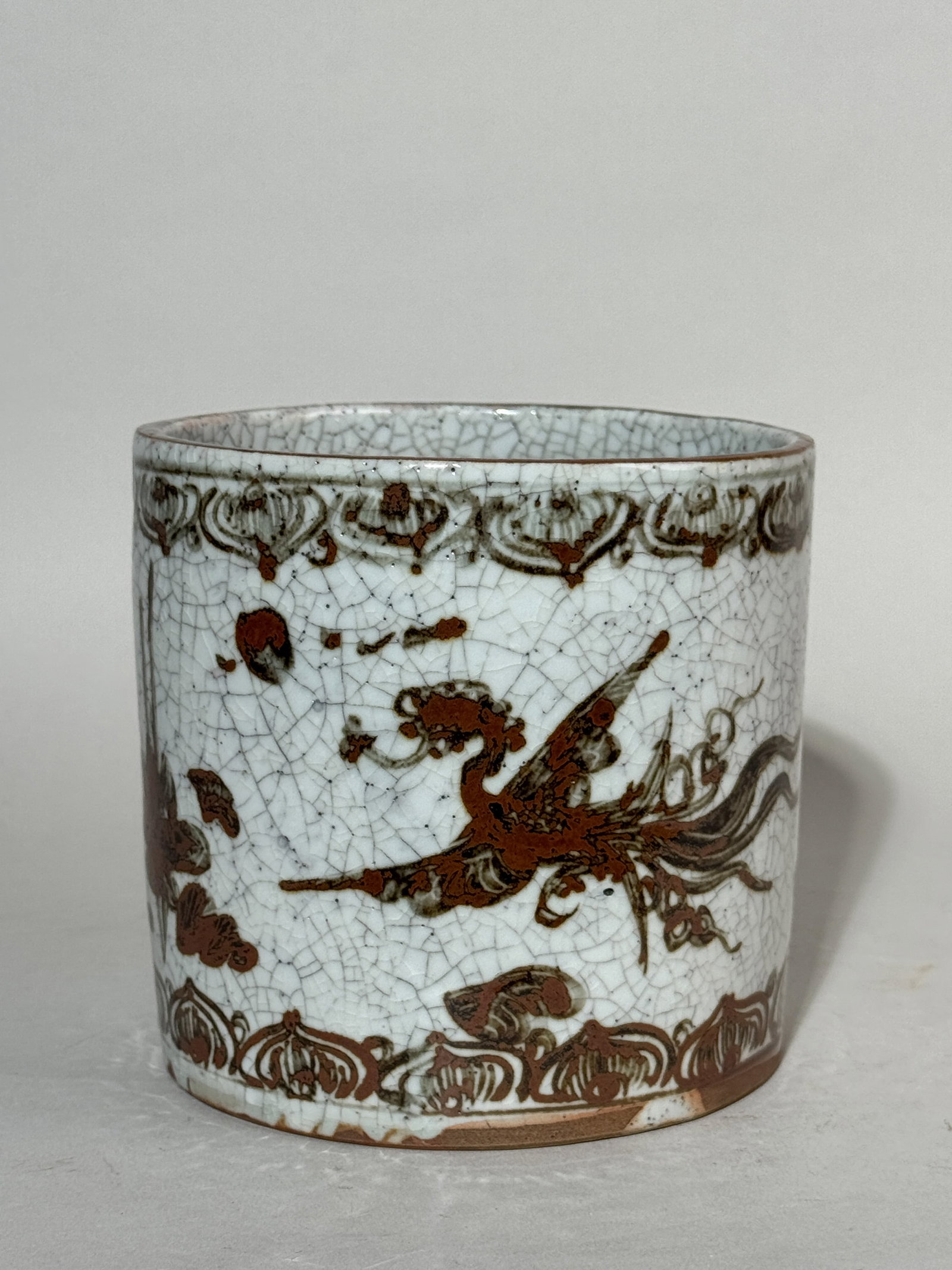 JAPANESE PORCELAIN BRUSHPOT WITH IRON RUST GLAZE PHOENIX: A Japanese porcelain brushpot with iron rust glazed phoenix decoration against a Ge crackle ground. Dimensions: Diameter: 5.5 in. (14 cm); Height: 5.25 in. (13.3 cm). Note: This item is in New York, w