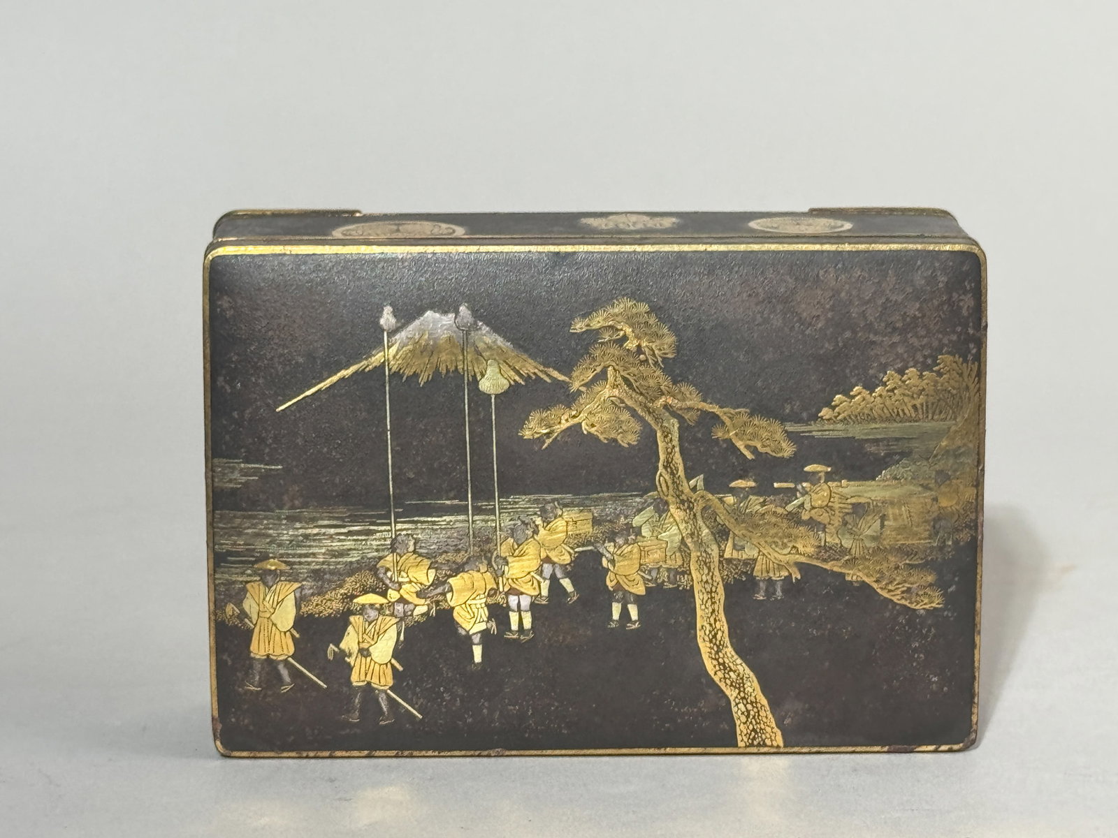 JAPANESE IRON MIXED METAL KOMAI BOX: A Japanese iron mixed metal Komai box, Meiji period, signed, depicting a samurai marching scene. Dimensions: 4.75 x 3.25 in. (12.1 x 8.3 cm). Note: This item is in New York, where it can be shipped fr