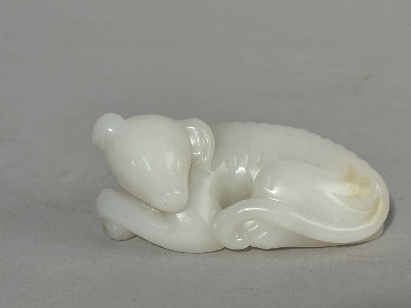 CHINESE WHITE JADE DOG: A Chinese white jade carving of a reclining dog. Dimensions: Length: 2.9 in. (7.4 cm). Note: This item is in New York, where it can be shipped from.
