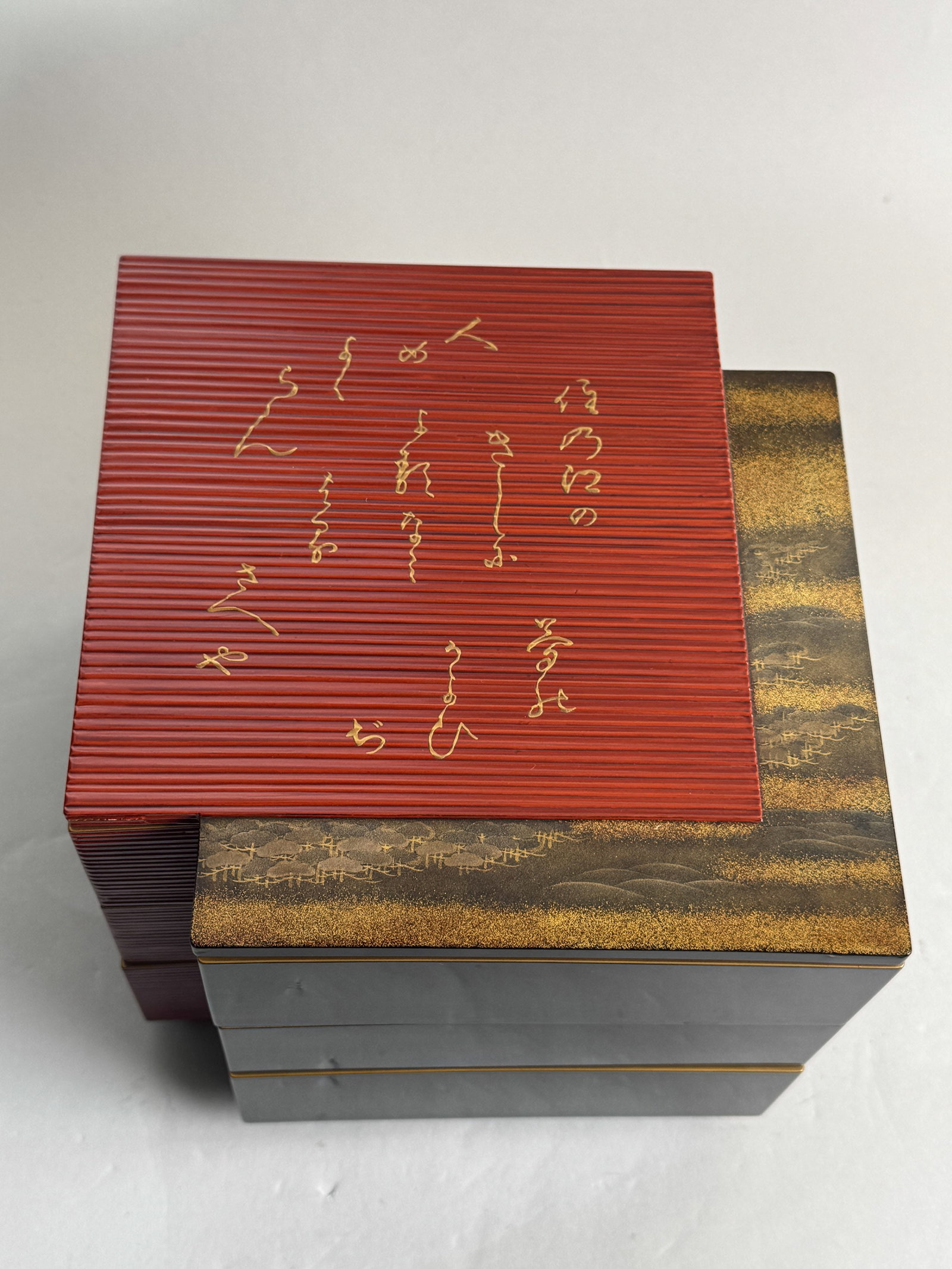 JAPANESE LACQUER BOX WITH POEM INSCRIPTION: A Japanese stacked lacquer box with a gold lacquer poem inscription on the cover. Dimensions: Width: 10 in. (25.4 cm); Height: 7 in. (17.8 cm). Note: This item is in New York, where it can be shipped 