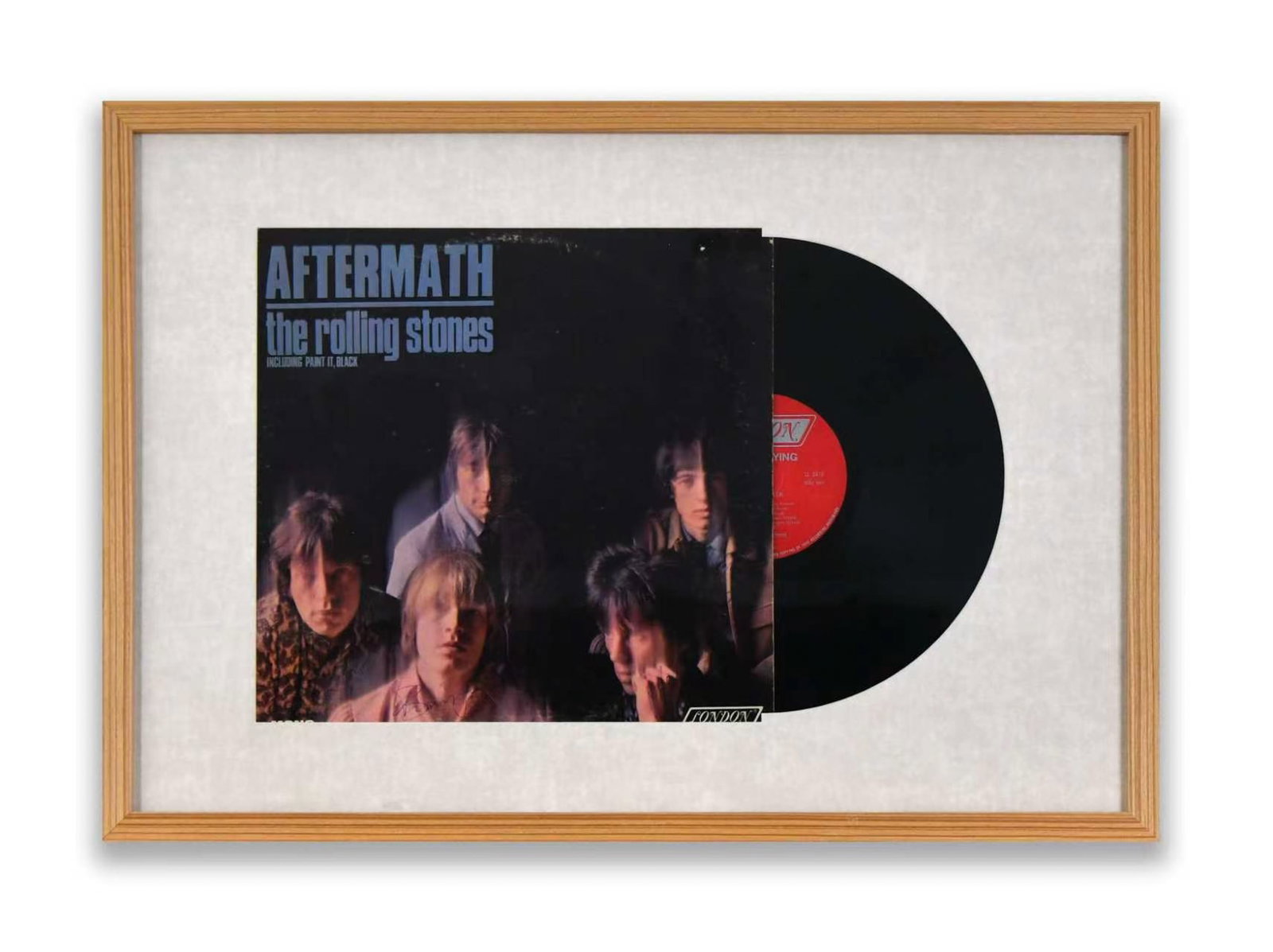 THE ROLLING STONES, ALBUM DISPLAY "AFTERMATH", BEARING SIGNATURES: The album sleeve is mounted to the left with the vinyl record partially revealed to the right. The album cover for 'Aftermath' provides a visual backdrop. The surface bears multiple ink marks of The R