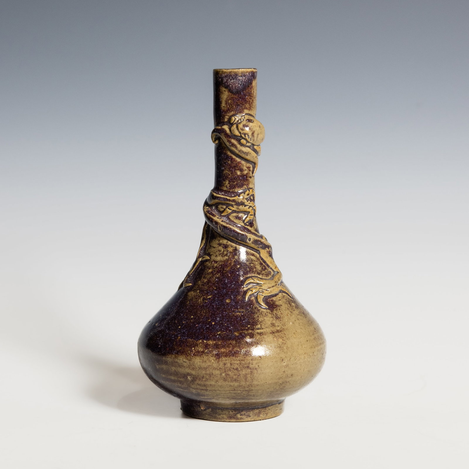 A Shiwan Ware Vase with Dragon Decoration, Qing Dynasty: A Shiwan ware vase, Qing Dynasty. Oslender cylindrical neck rising above a rounded body, the surface covered in a mottled purplish-brown and beige glaze. A vividly modeled applied dragon coils around