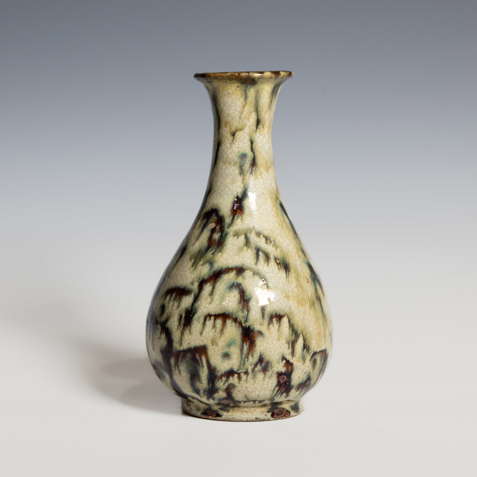 A Shiwan Ware Flambe-Glazed Vase, Qing Dynasty: A Shiwan ware vase of slender pear shape rising to a flared mouth rim, Qing dynasty . The body covered overall with a crackled cream glaze suffused with flamb?? streaks in tones of teal, aubergine,