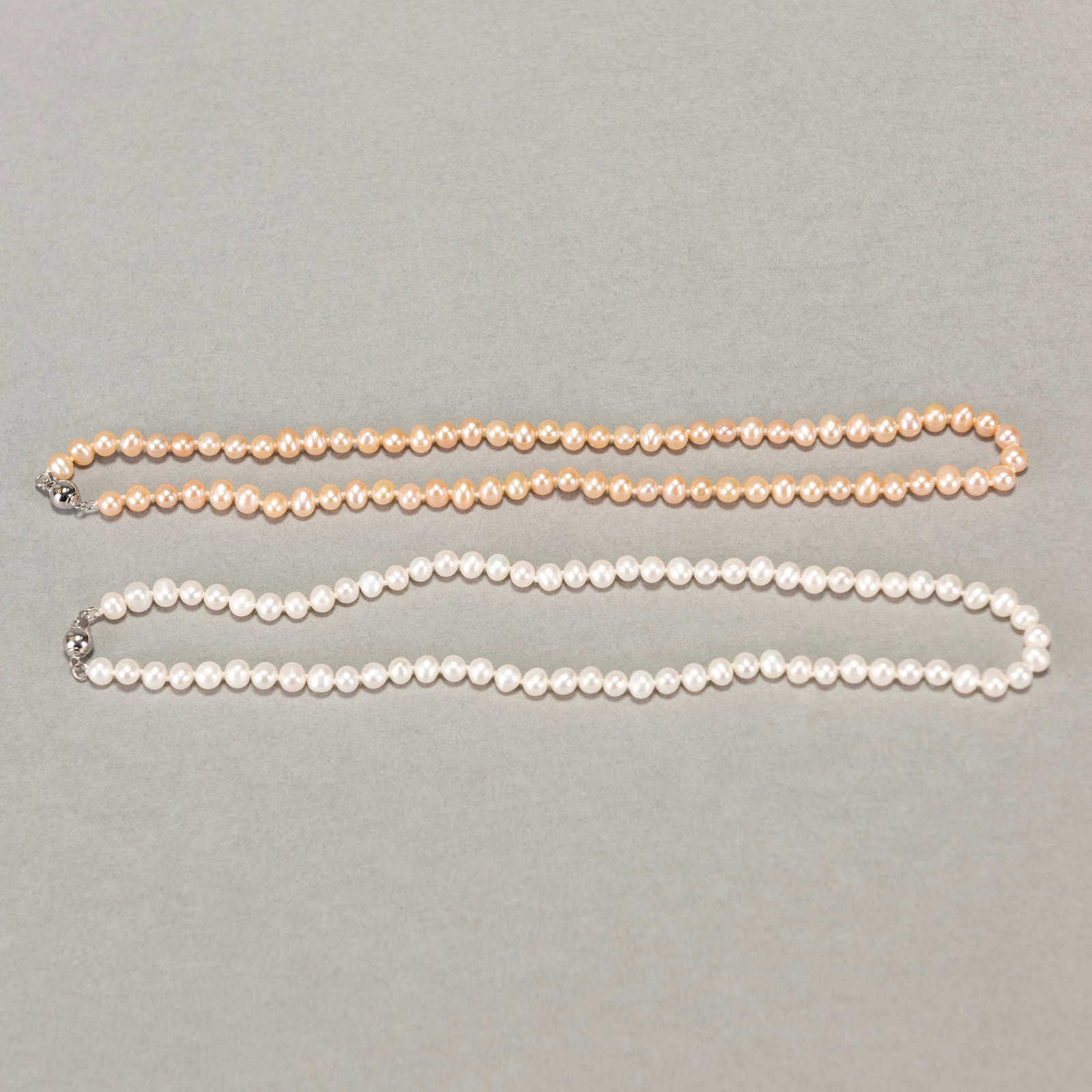 TWO STRANDS OF WHITE AND PEACH PEARL NECKLACES: (lot of 2) Two strands of white and peach pearl necklaces. Approx. length: 16.93"l (43 cm)
