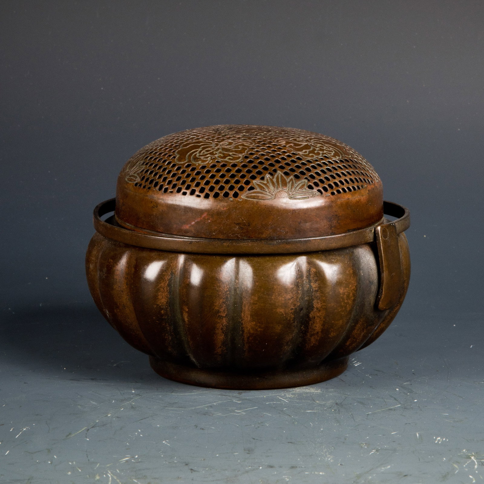 A LOTUS-SHAPED BRONZE CENSER: A lotus-shaped bronze censer, openwork lid with flower pattern, bottom sealed, with a half-ring handle. Diameter: 5"; height: 3.75"