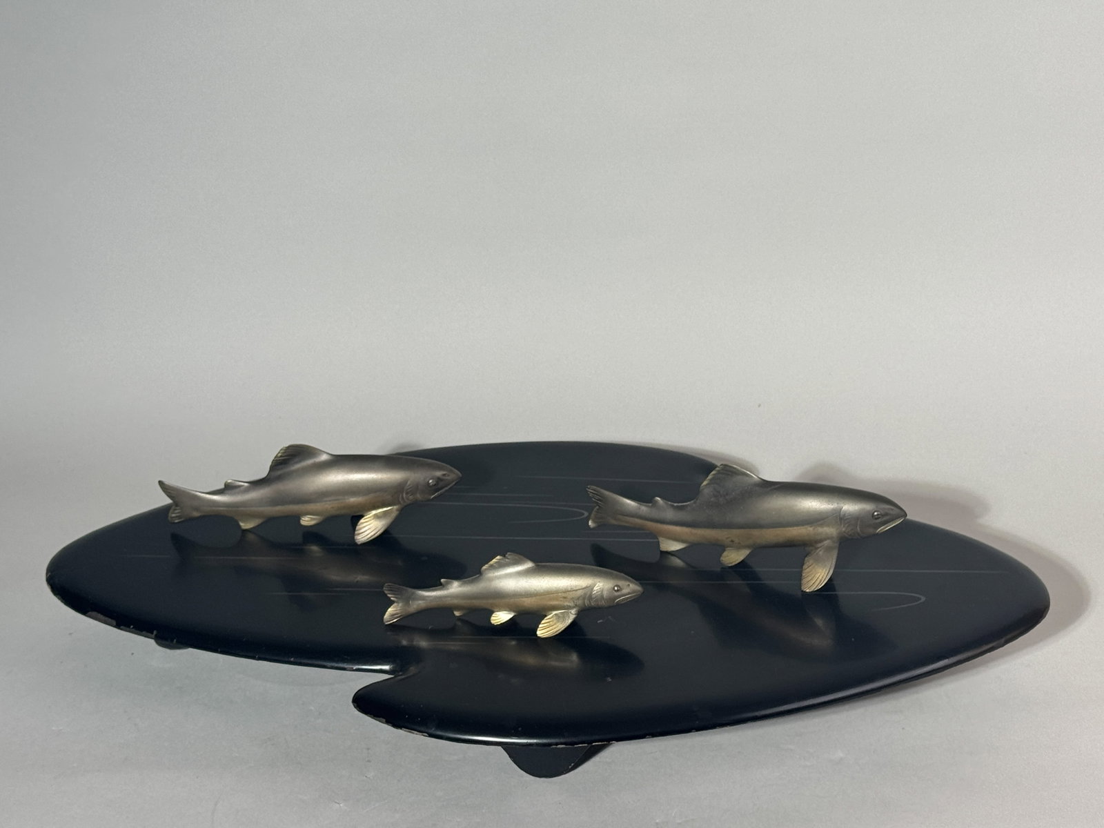 JAPANESE MIXED METAL KOI GROUP ON LACQUER STAND: A Japanese mixed metal koi group, Taisho period, signed, resting on a lacquer stand. The stand has some chips on the lacquer. Dimensions: Largest koi length: 7 in. (17.8 cm); Stand width: 22 in. (55.9
