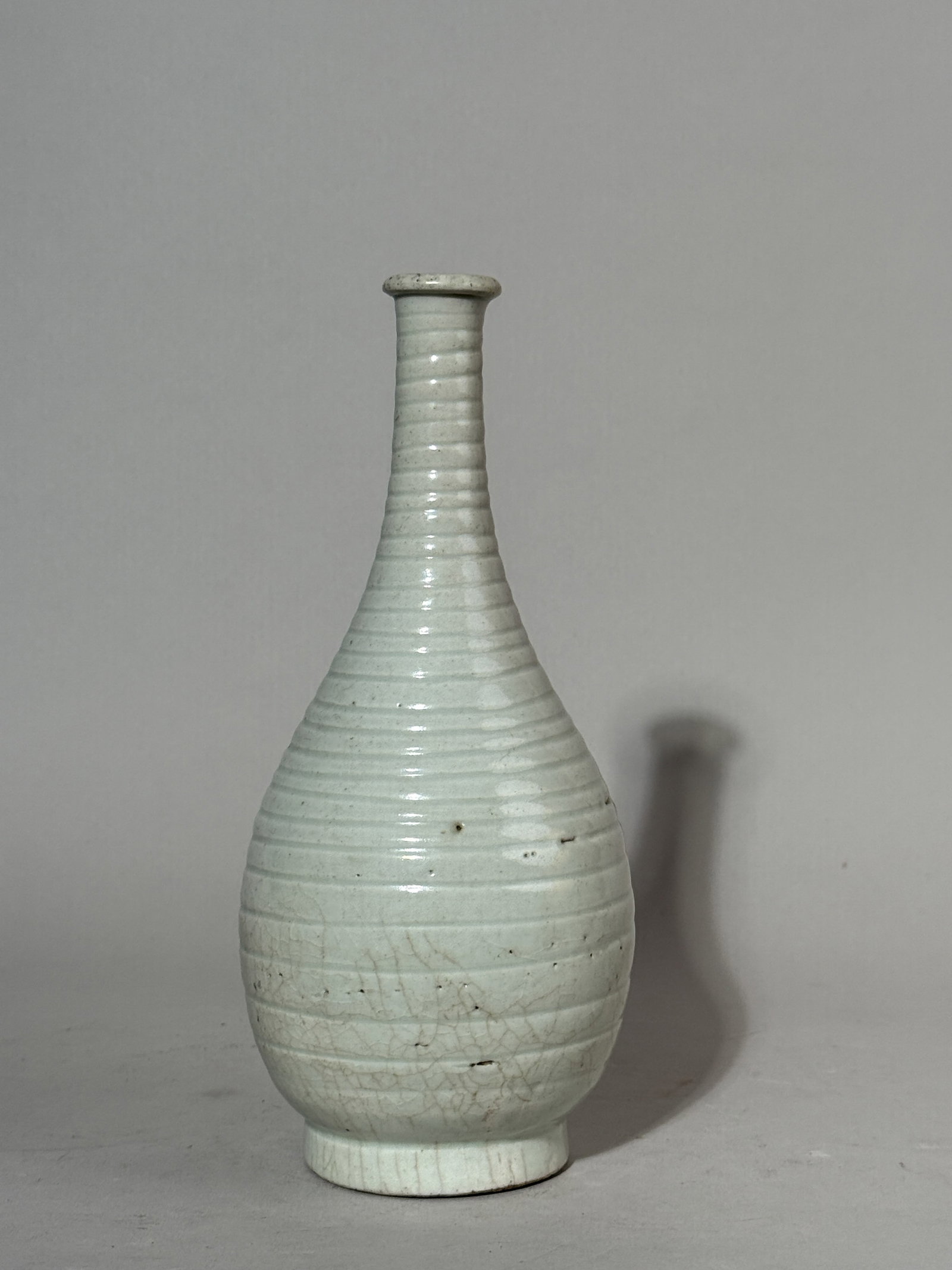 KOREAN LONG-NECK PORCELAIN VASE WITH RIBBED BODY: A Korean ribbed porcelain vase with a long neck. Dimensions: Height: 9 in. (22.9 cm). Note: This item is in New York, where it can be shipped from.