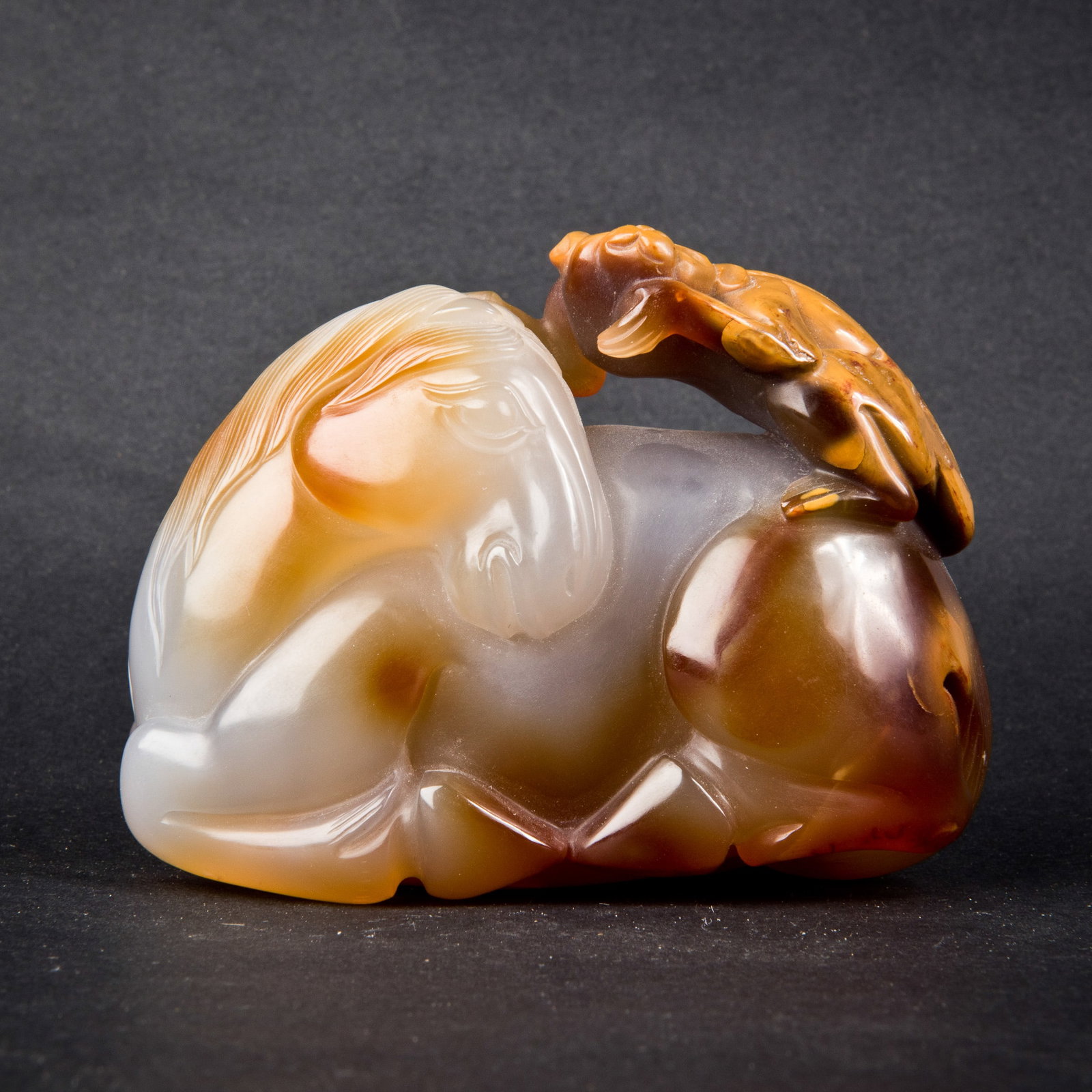 MONKEY AND HORSE AGATE ORNAMENT: An agate ornament formed as a monkey on a horse, symbolizing "promotion soon coming," with brownish suffusions. Length: 3.5"; width: 1.75"; height: 2.75"