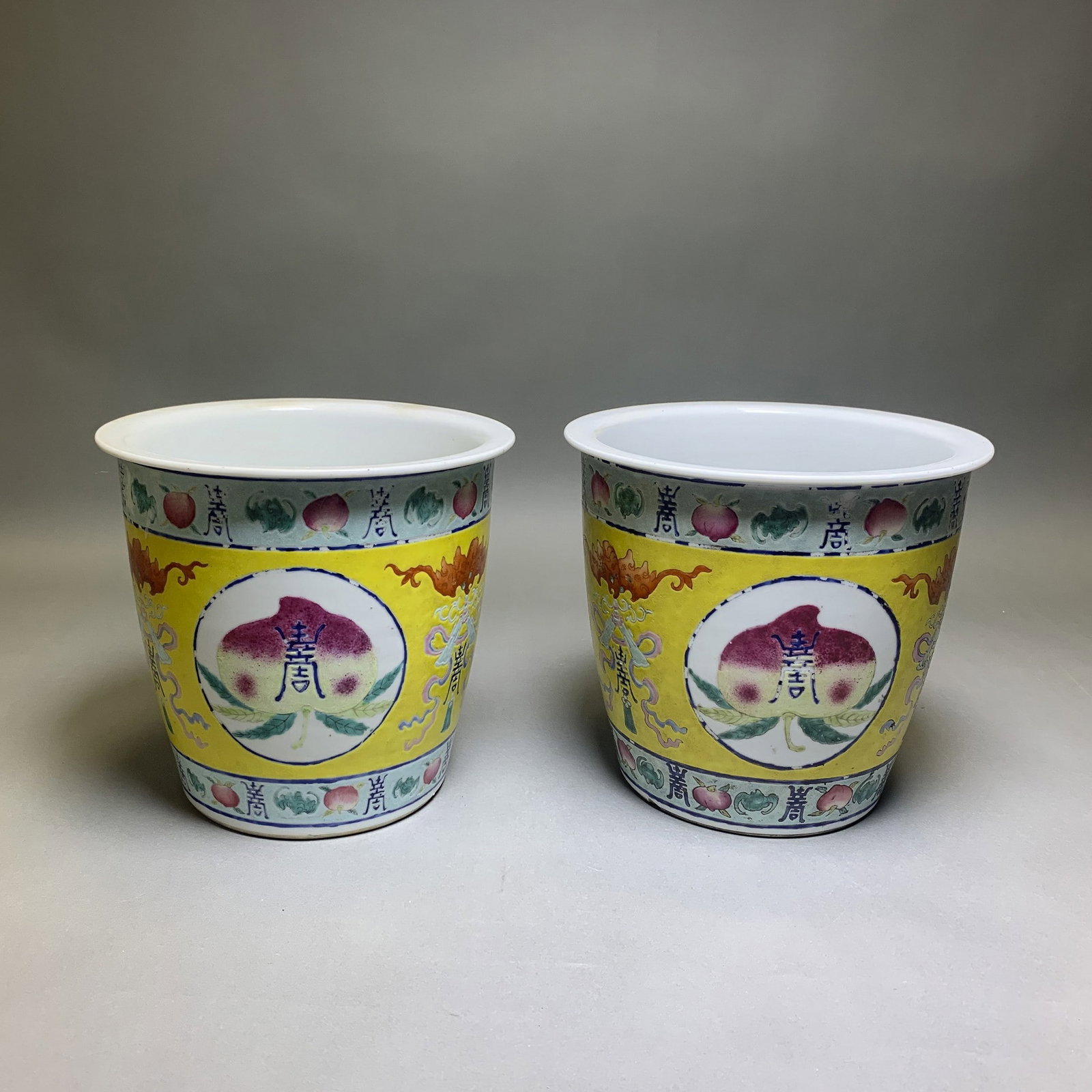 PAIR OF FAMILLE ROSE "PEACH" JARDINIERES, 19TH CENTURY: (lot of 2) Pair of famille rose "peach" jardinieres, 19th century, each of cylindrical form to a tapering foot, decorated with roundels enclosing peaches, each divided by a bat and bajixiang. 6.69"h x