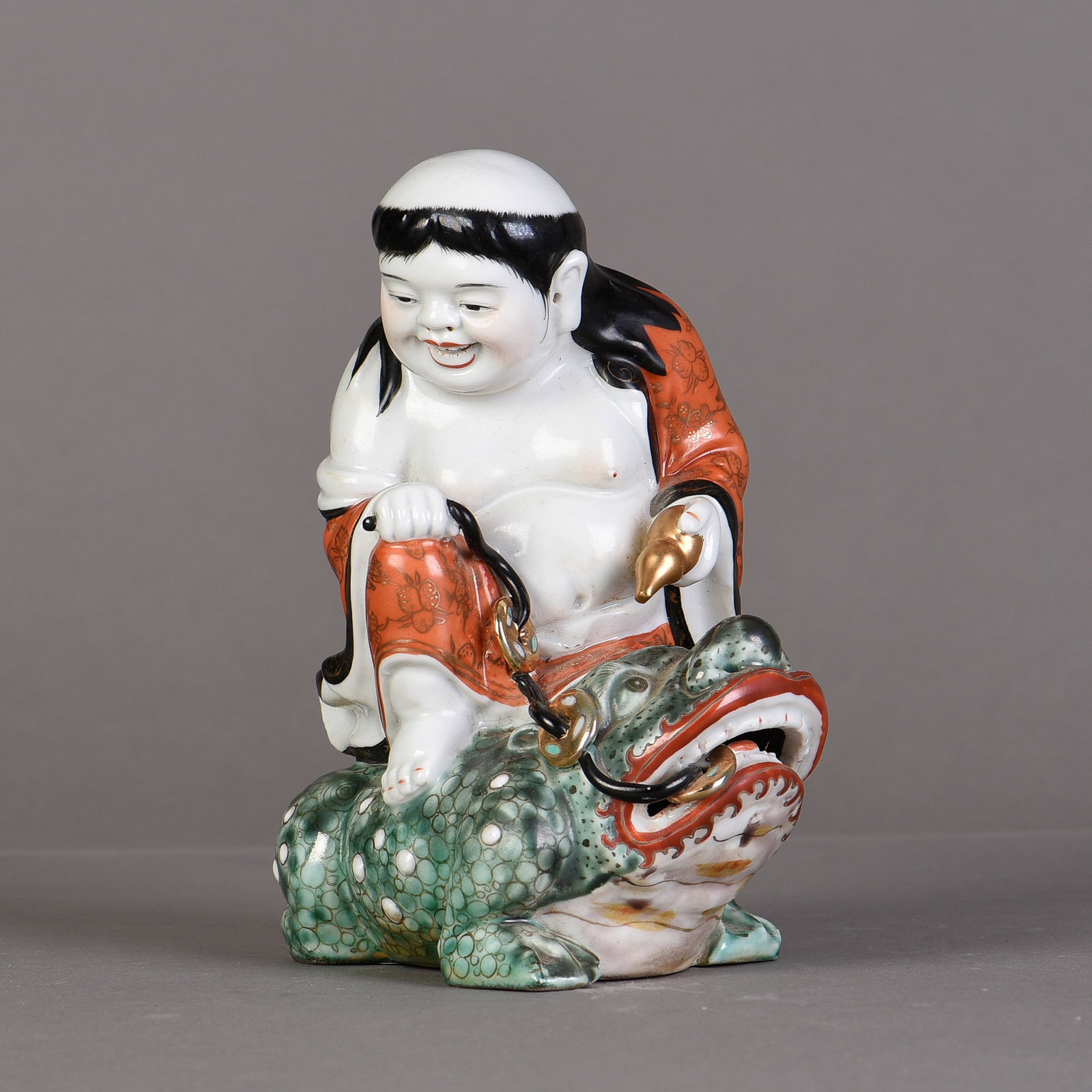 A FAMILLE ROSE PORCELAIN SCULPTURE: A famille rose sculpture of Liu Hai playing with Jin Chan, four-character seal molded on the base. 7"h x 5.5"w x 4"l (17.78 x 13.97 x 10.16 cm)