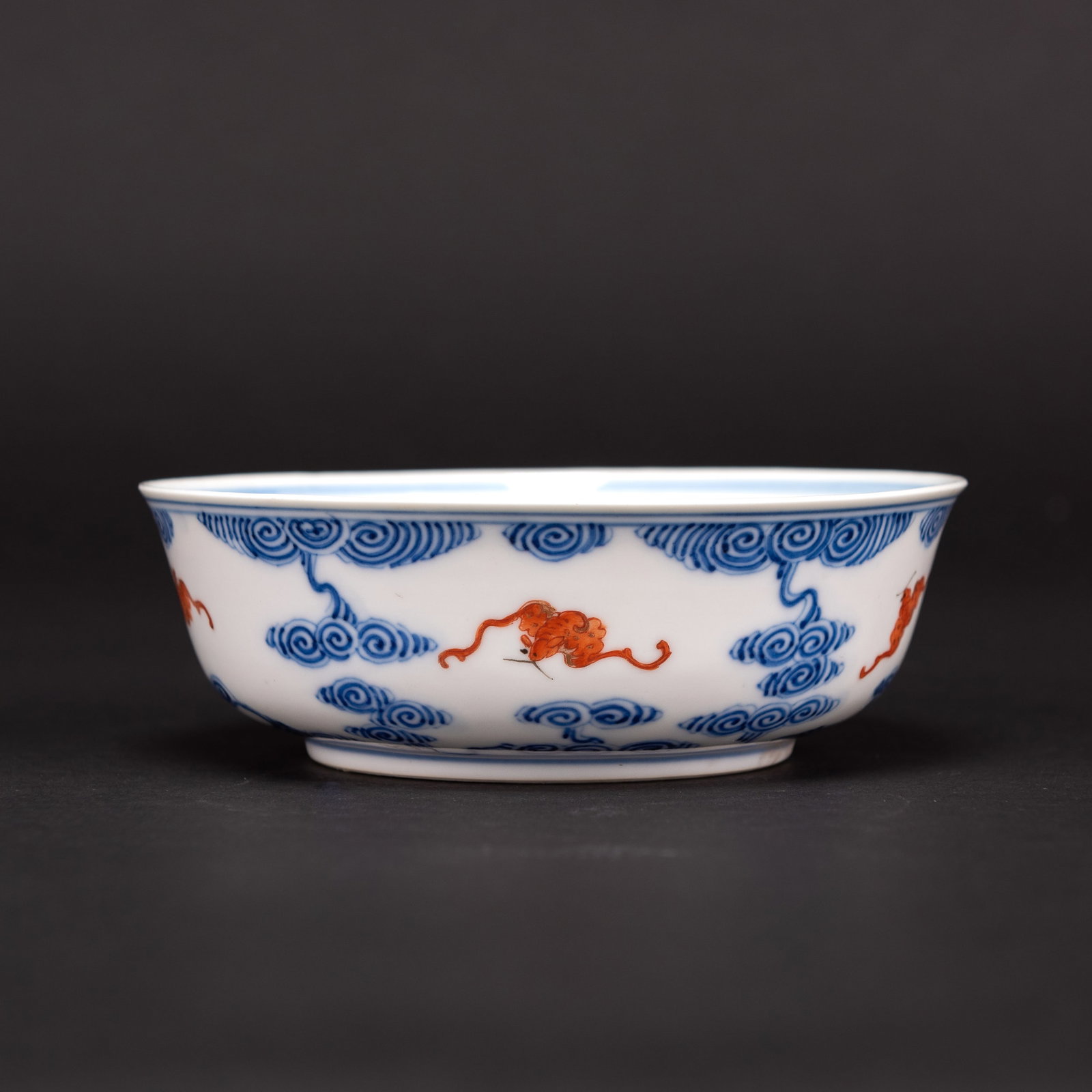 CHINESE BLUE AND WHITE AND IRON RED "BAT" BOWL: Chinese blue and white and iron red "bat" bowl. A blue and white and iron red "bat" bowl, potted with deep rounded sides, exterior decorated with five iron-red bats amongst scrolling clouds, and