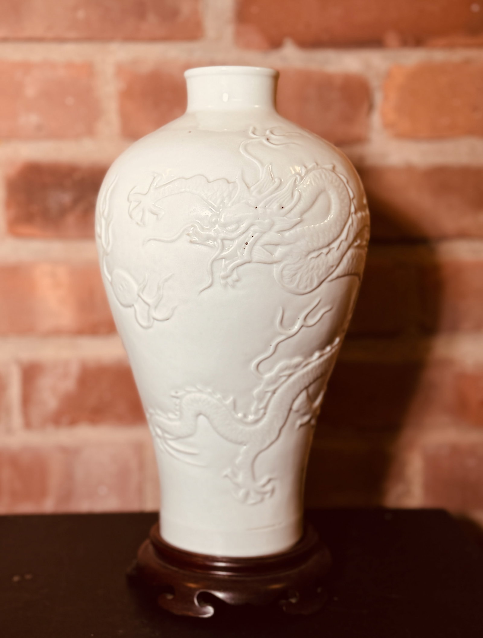 JAPANESE STUDIO PORCELAIN VASE WITH RAISED DRAGON MOTIF: Japanese white-glazed porcelain vase with moriage dragon motif, on a hardwood base with an old label. Dimensions: Vase Height: 10.75 in. (27.3 cm). Note: This item is in New York, where it can be ship