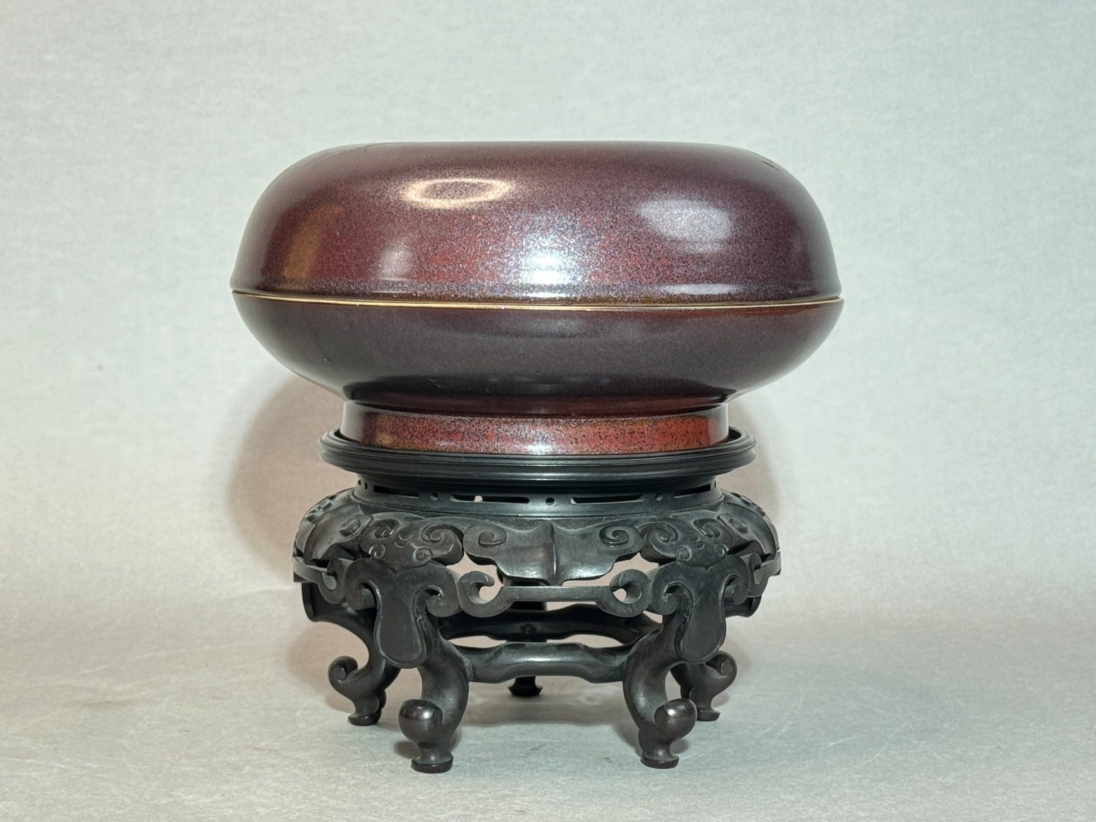 CHINESE IRON-RUST-GLAZED PORCELAIN ROUND COVERED BOX: Antique 18th-century Chinese porcelain covered box with iron-rust glaze, unsigned, on a carved wood stand. Dimensions: Diameter: 10 in. (25.4 cm); Height: 5 in. (12.7 cm). Note: This item is in New