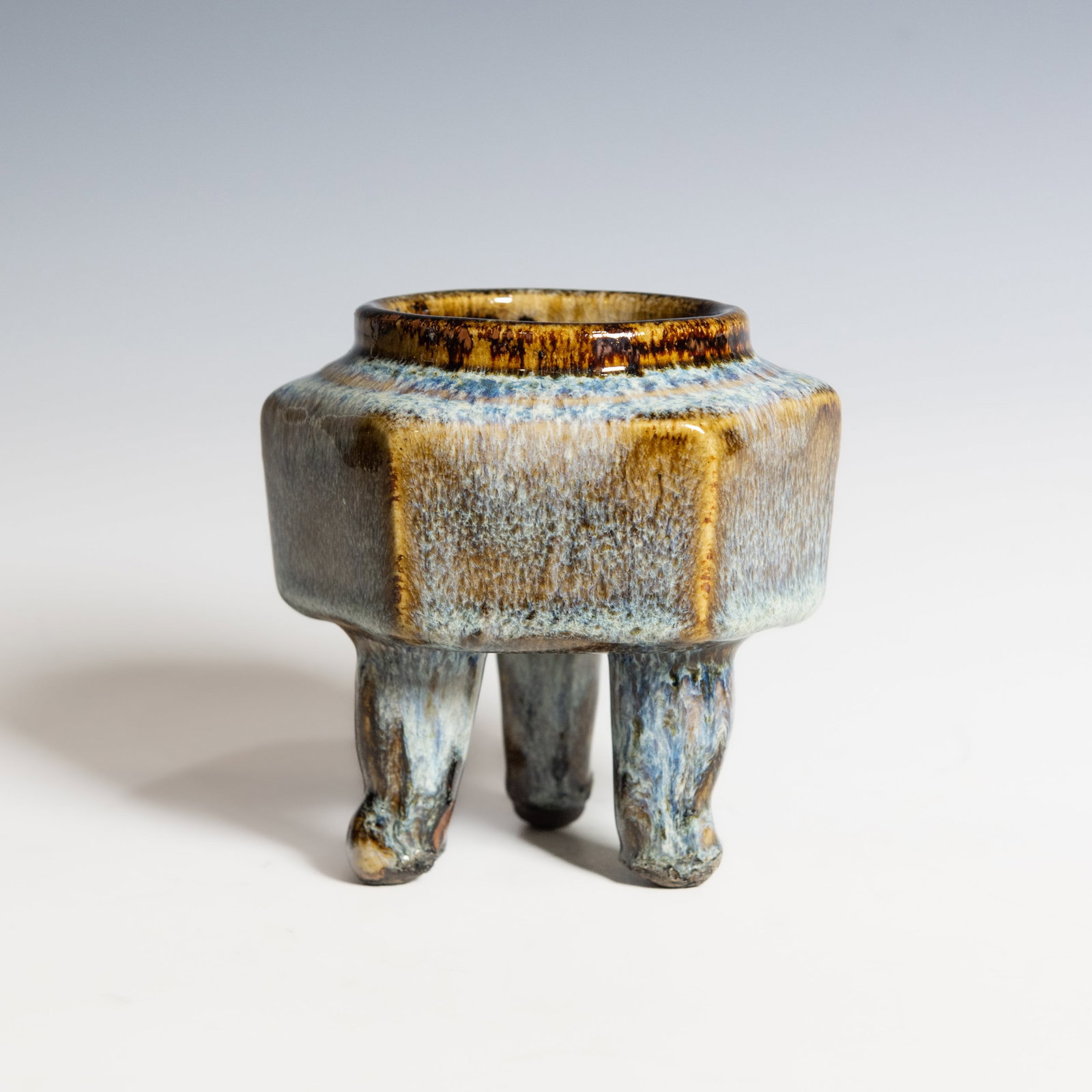 A SHIWAN WARE GLAZED TRIPOD CENSER, QING DYNASTY: A Shiwan ware glazed tripod censer of hexagonal form, Qing dynasty, supported on three splayed feet. The exterior is decorated with a rich transmutation glaze ranging from sky blue to amber brown,