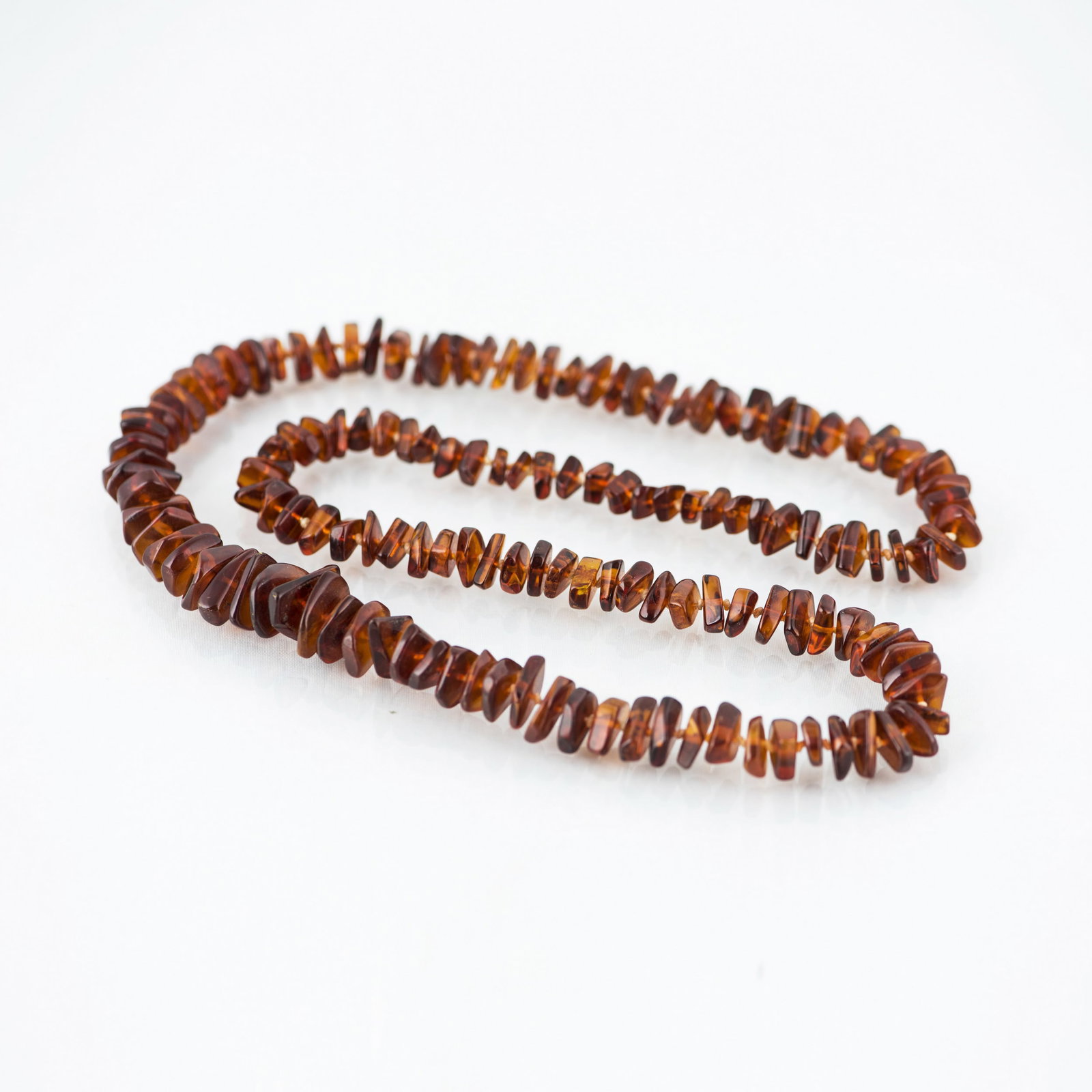 AMBER PRAYER BEADS: Long strand of dark-colored amber prayer beads of natural form. 32"l (81.28 cm)
