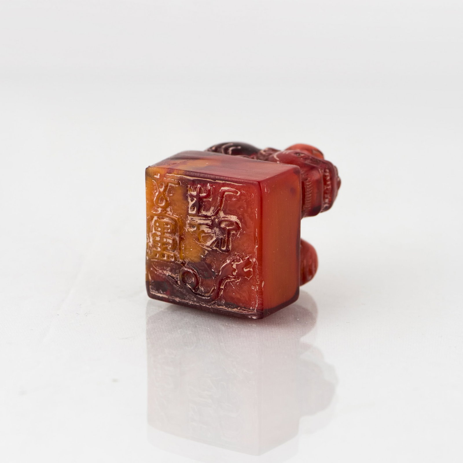 CARVED RED STONE SEAL: A carved red stone seal, possibly agate, surmounted by a crouching mythical beast. 1.5"h x 1.5"w x 1.5"l (3.81 x 3.81 x 3.81 cm)