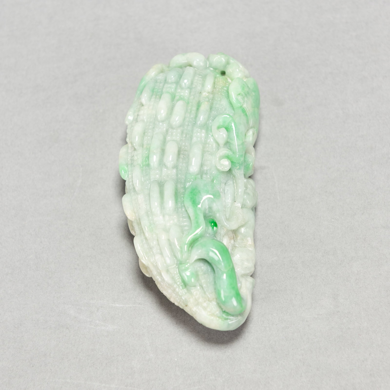 CARVED JADEITE BITTER-GOURD ORNAMENT: Carved jadeite bitter-gourd ornament. 3.74"h x 0.98"w x 1.97"l (9.5 x 2.5 x 5 cm); 102.1 dwt