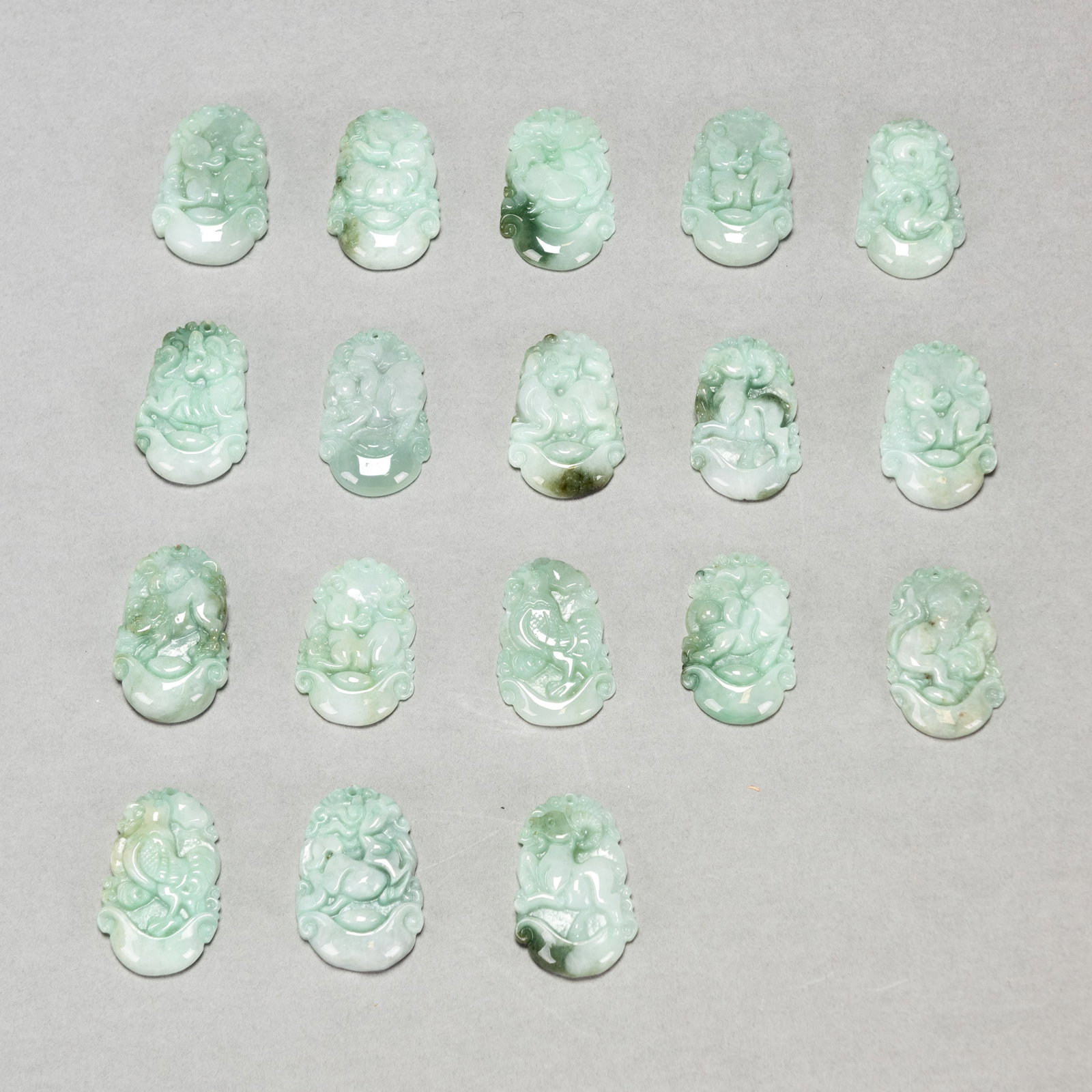 (LOT OF 18) GROUP OF EIGHTEEN JADEITE ZODIAC PENDANTS: (lot of 18) Group of eighteen jadeite zodiac pendants. Approximately 1.38"h x 0.79"w x 0.2"l (3.5 x 2 x 0.5 cm); 120 dwt