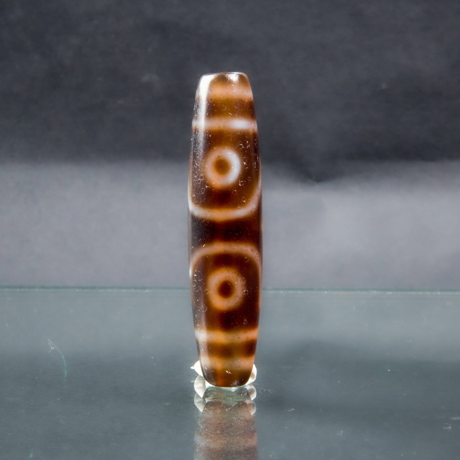 BROWN DZI BEAD: A finely polished brown Dzi bead with a natural pattern. 2.25"h x 0.5"d (5.72 x 1.27 cm)