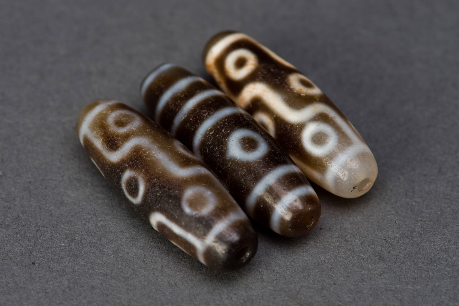 (LOT OF 3) THREE SMALL DZI BEADS: (lot of 3) Three small Dzi beads. 1.25"h x 0.25"d (3.18 x 0.64 cm) (x3)