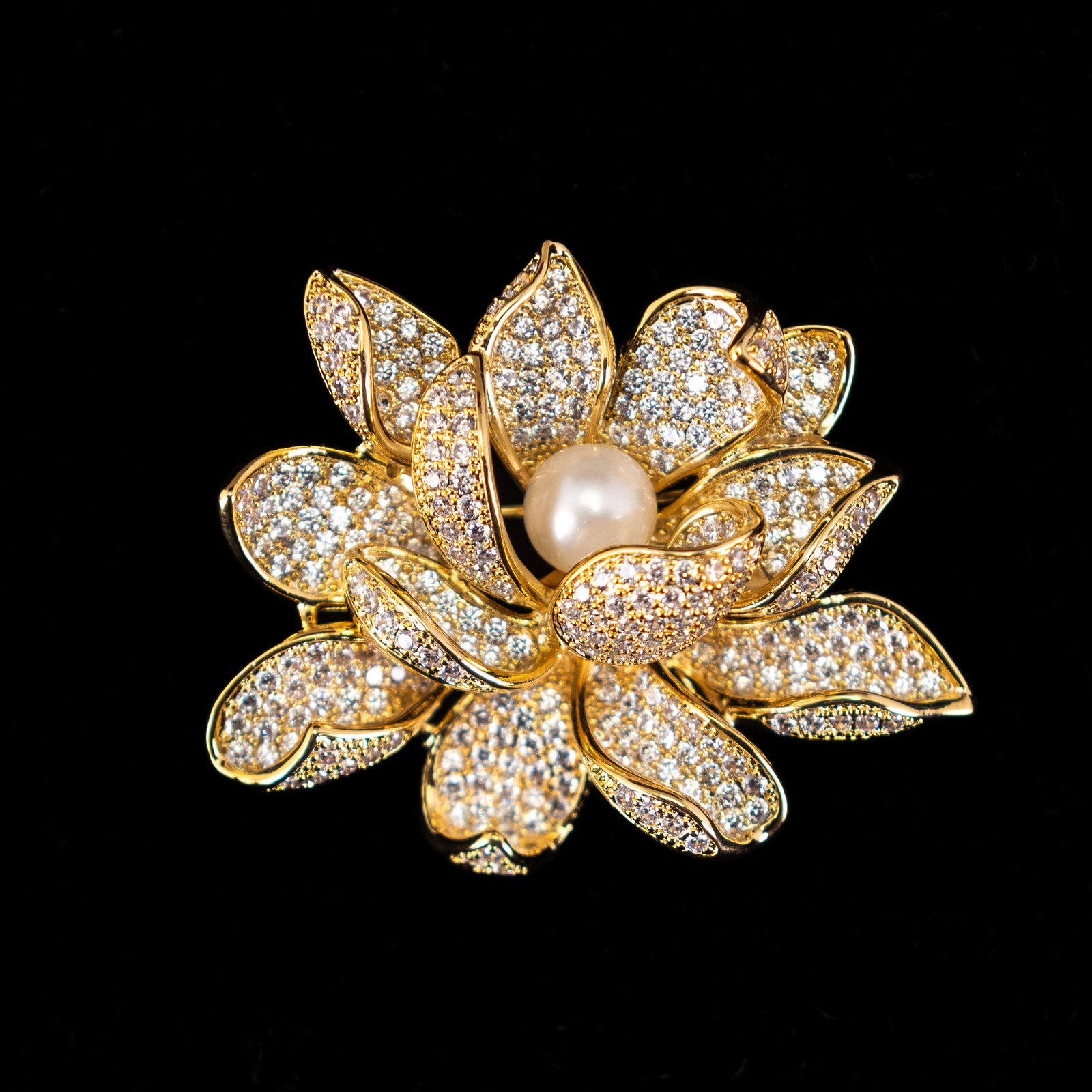 A FASHION JEWELRY DIAMOND-STYLE PEARL BROOCH: A fashion jewelry diamond-style brooch in the form of a flower, with a pearl in the center. 5 x 4 cm