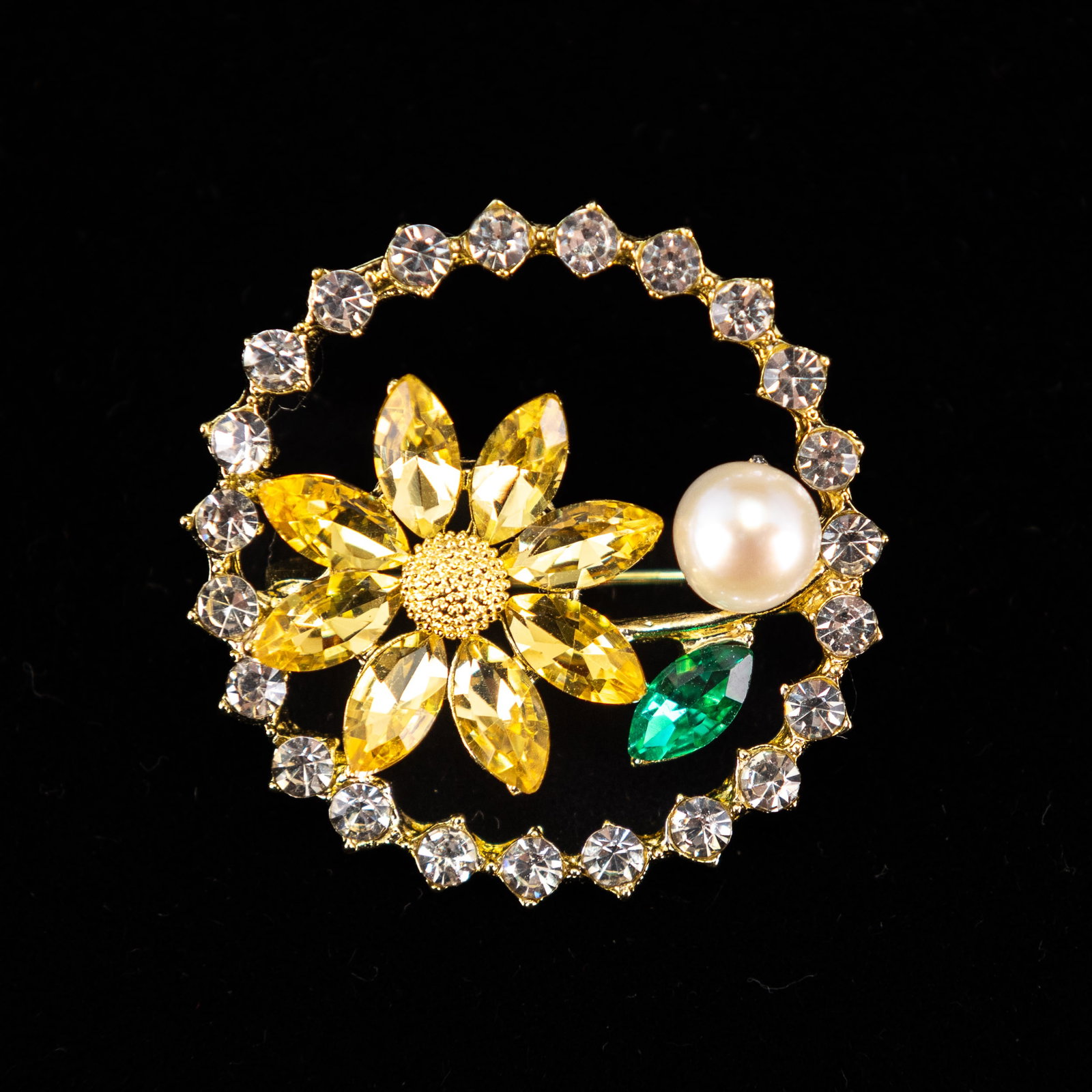 A FASHION JEWELRY PEARL BROOCH: A fashion jewelry pearl brooch in the form of a flower, with a pearl in the center. 3 x 3 cm