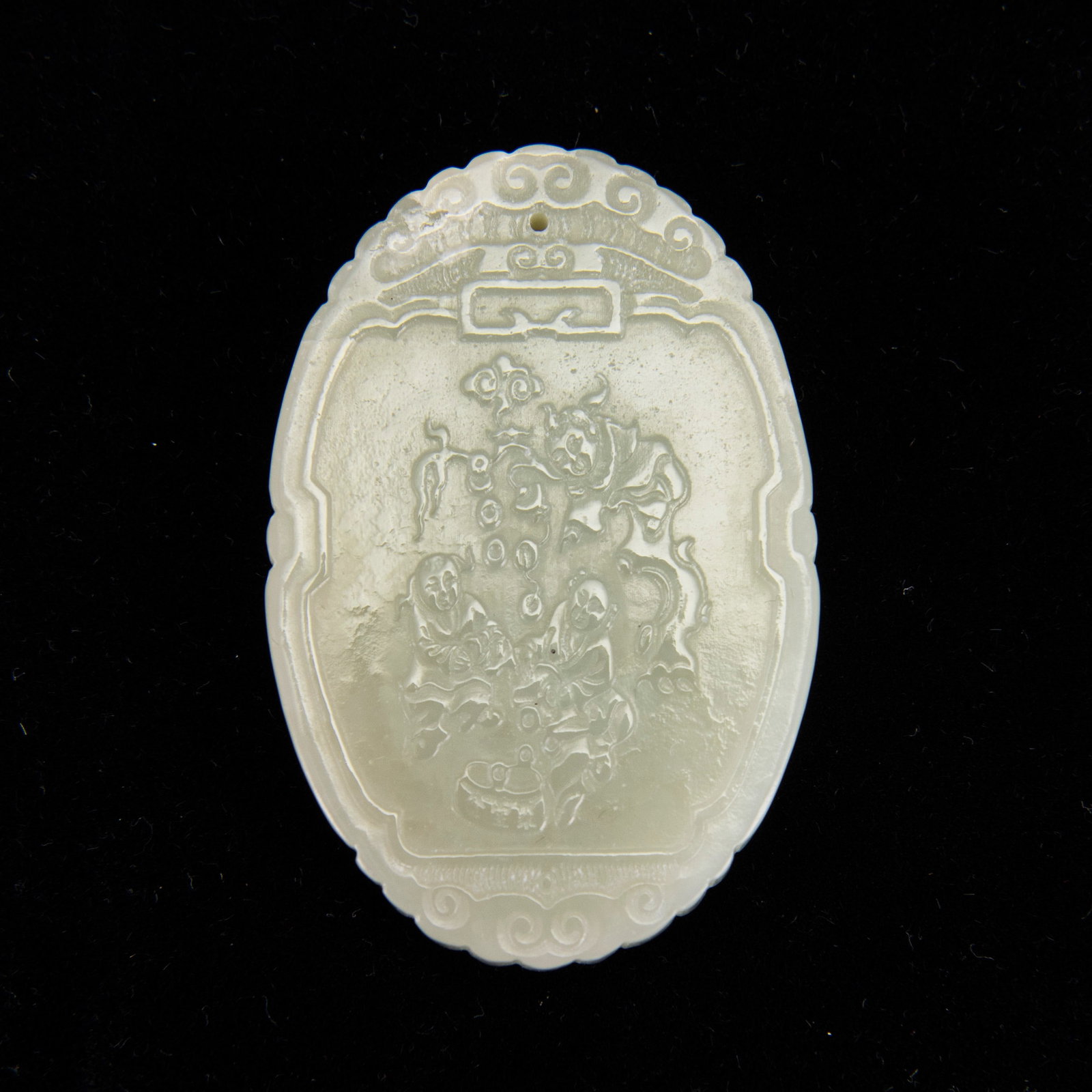 A GREEN JADE OVAL PENDANT: A green jade oval pendant, carved in relief with figures and calligraphy. 6.8 x 4.35 cm Provenance: Estate sale from Reno, NV.