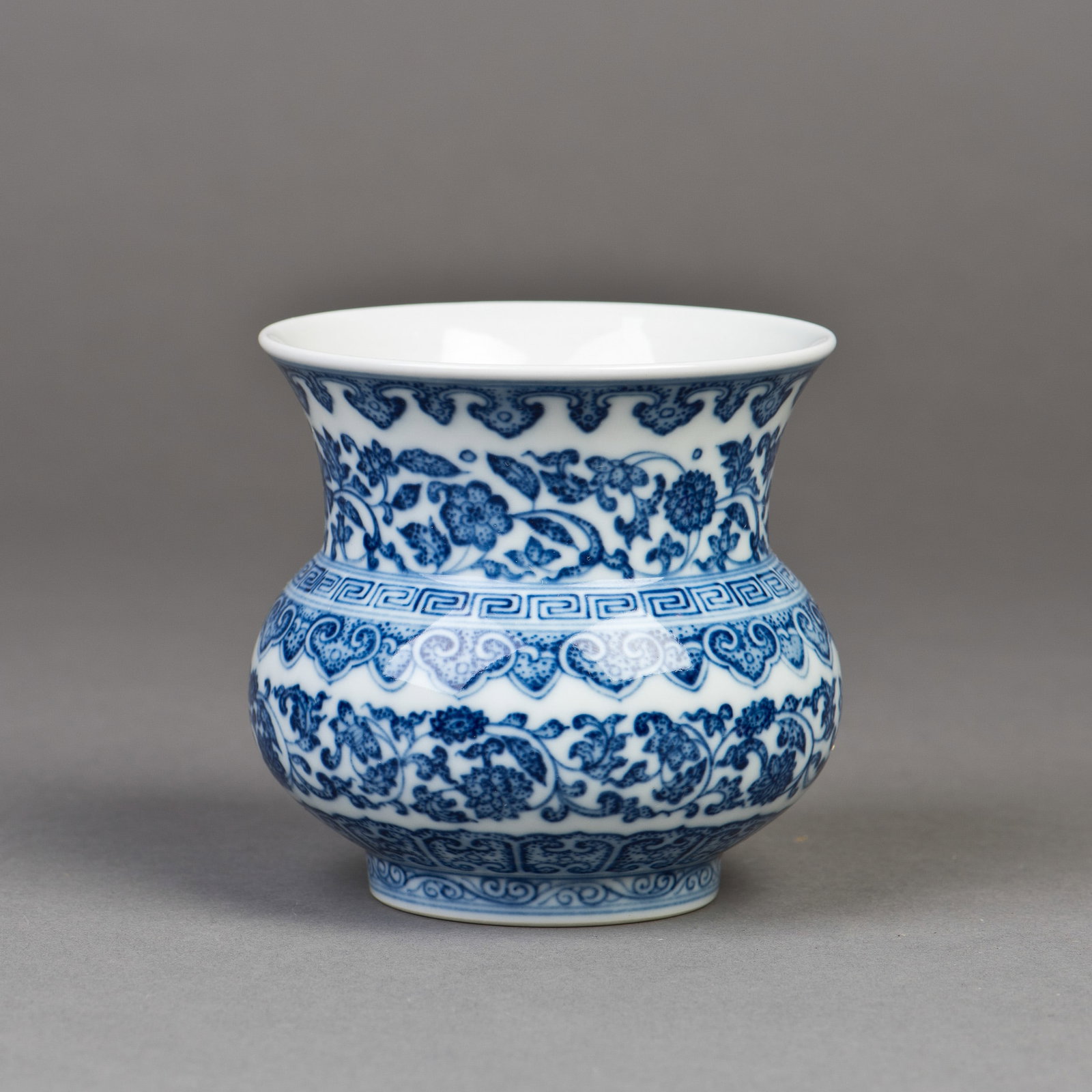 A CHINESE BLUE-AND-WHITE PORCELAIN VASE: A Chinese blue-and-white porcelain vase with a wide mouth and neck, a compressed body supported on a short foot, and foliate decoration. A six-character seal mark is on the base. 4"h x 4"w (10.16 x