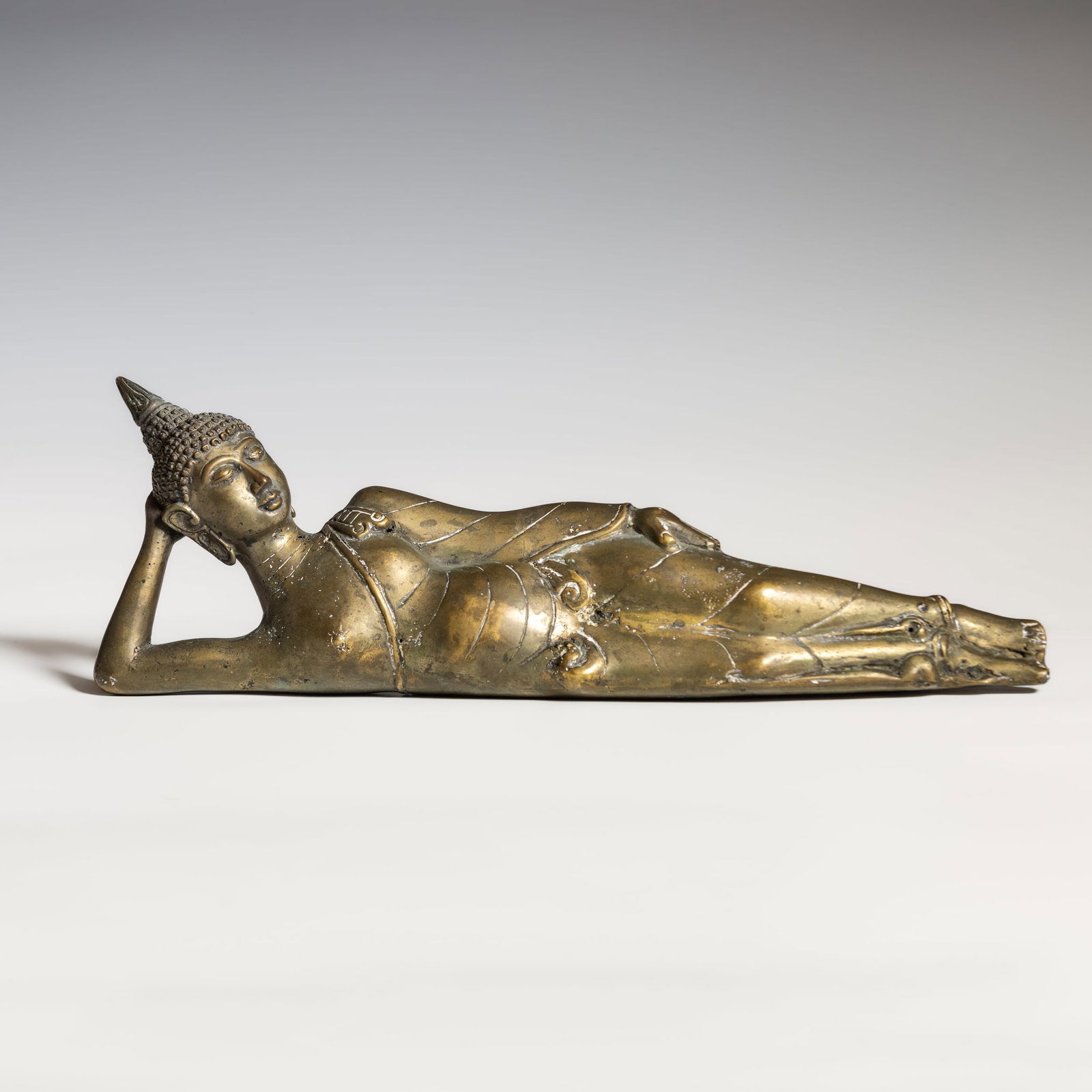 GILT-BRONZE FIGURE OF RECLINING BUDDHA: Gilt-bronze figure of reclining Buddha. 5.12"h x 14.76"w x 2.76"l (13 x 37.5 x 7 cm)