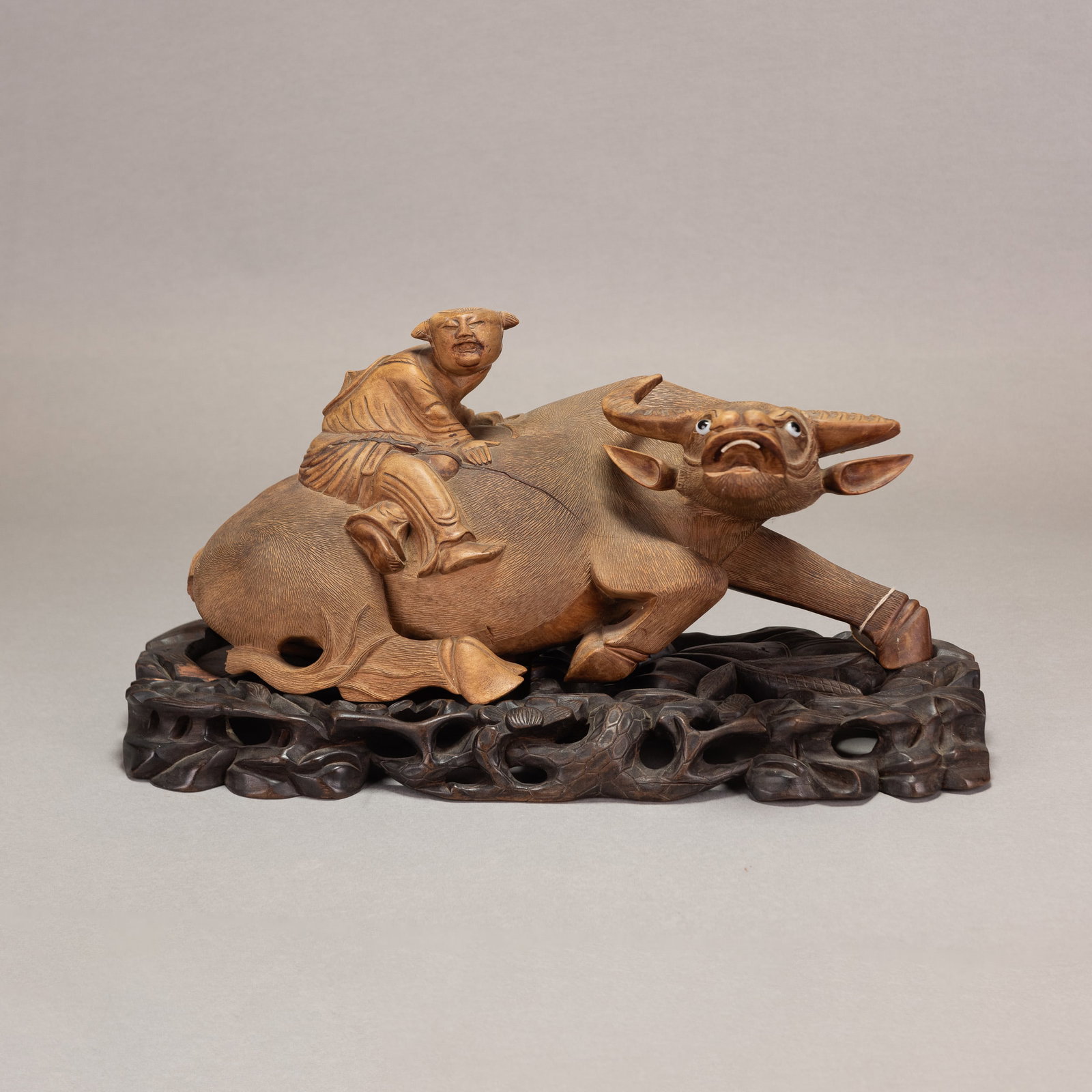 CHINESE CARVED WOODEN BUFFALO AND BOY: Chinese carved wooden buffalo and boy, with original wooden stand. Overall (with base): 8.27"h x 7.48"w x 16.54"l (21 x 19 x 42 cm)