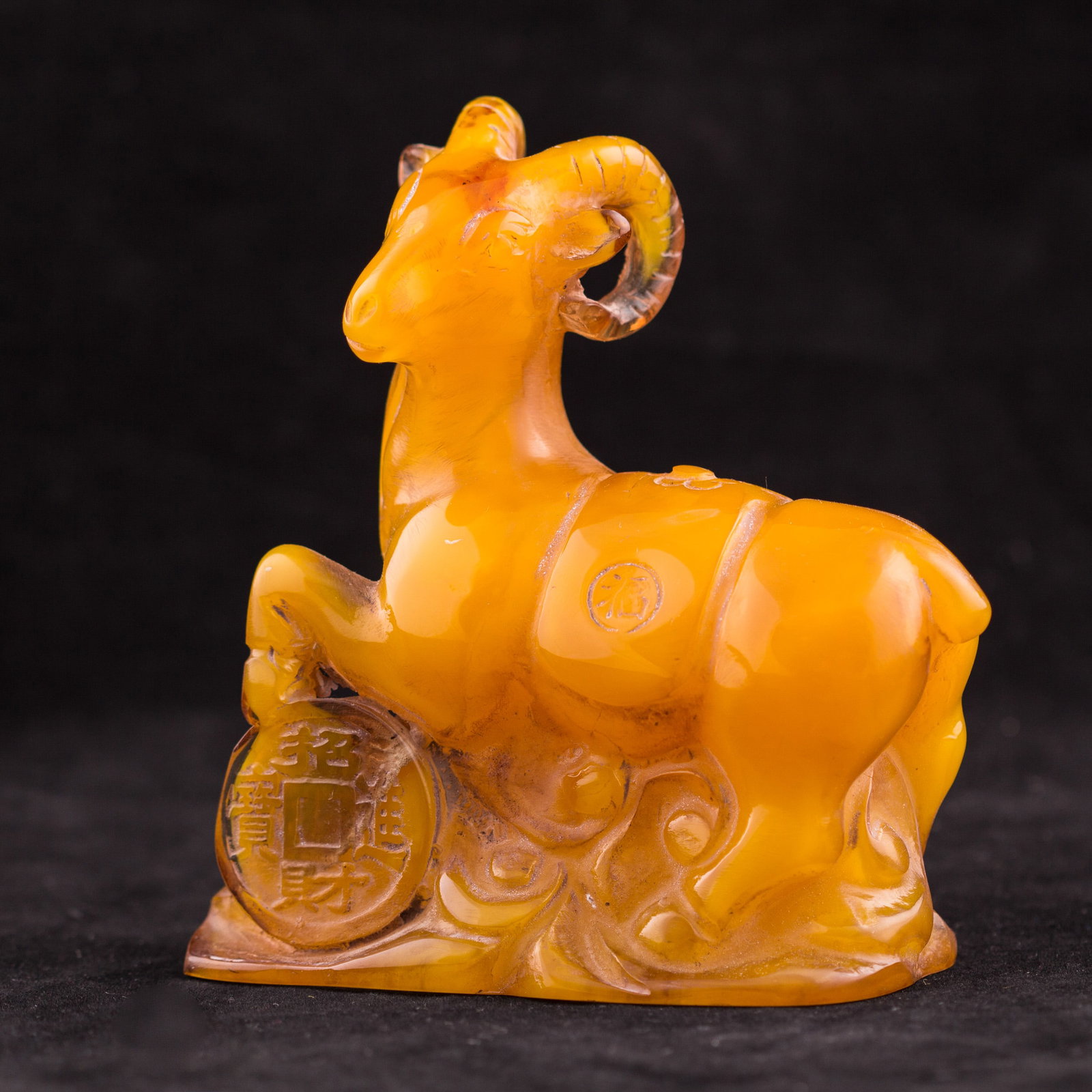 A CARVED ORNAMENT OF A GOAT: Amber-colored ornament carved as a goat standing on a coin. 4.5"h x 2"w x 4"l