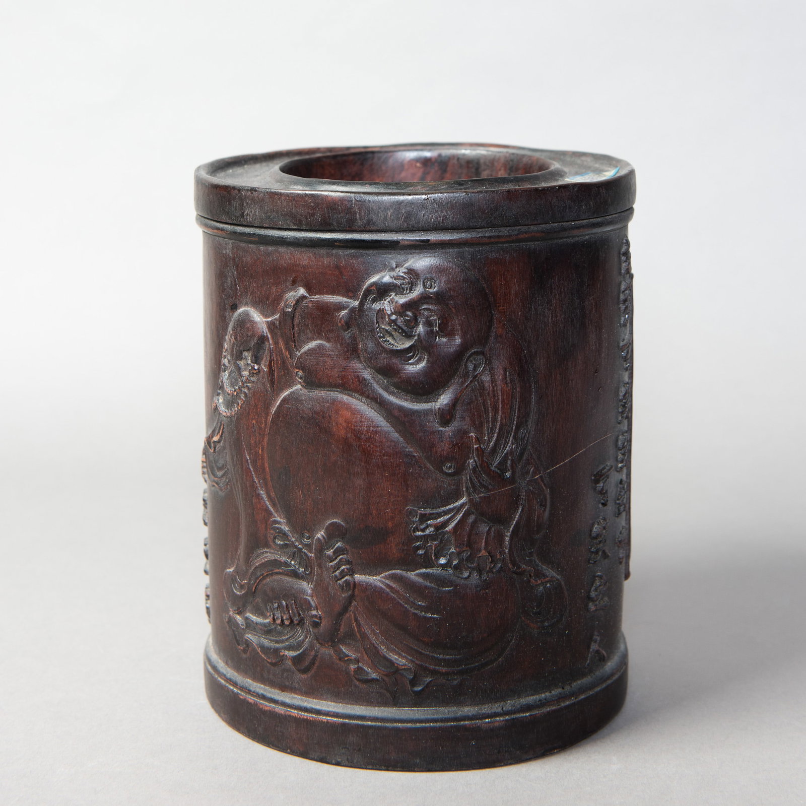 A CARVED HARDWOOD BRUSH POT: A carved hardwood brush pot of cylindrical form, carved in low relief with figures. 7.5"h x 6.25"d (19.05 x 15.88 cm)