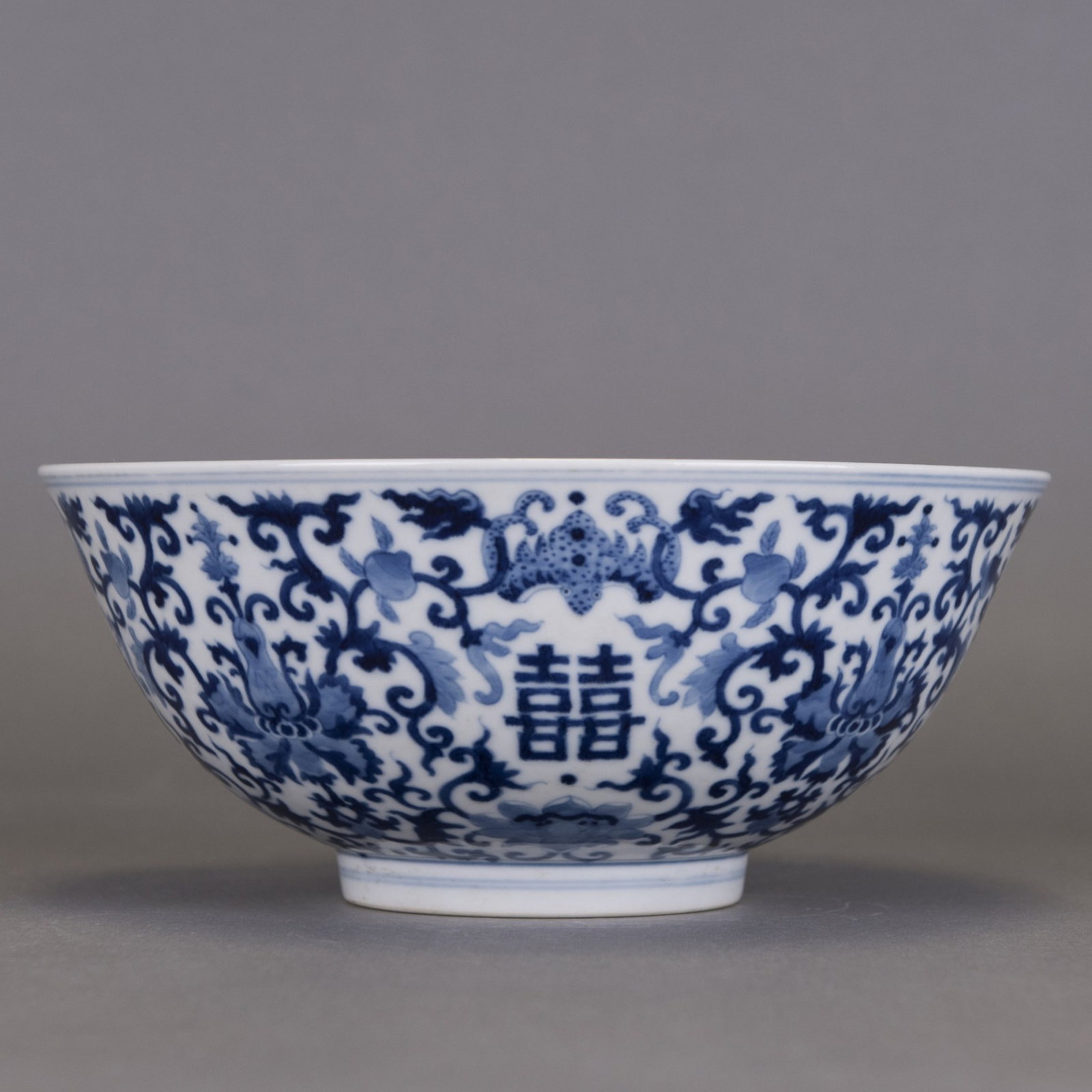 A CHINESE BLUE-AND-WHITE PORCELAIN BOWL: A Chinese blue-and-white porcelain bowl, finely painted in deep cobalt blue with scrolling lotus and stylized shuangxi (double happiness) characters around the exterior.