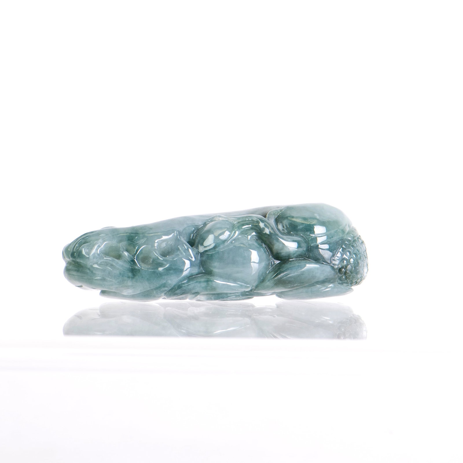 A CARVED JADEITE PENDANT: A carved jadeite pendant with a decoratively carved stone of a translucent green tone. 3"h x 0.8"w x 1.25"l (7.62 x 2.03 x 3.18 cm)