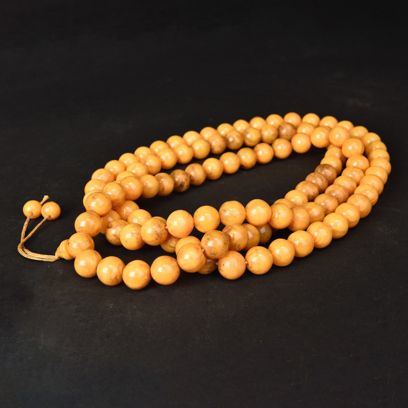 A STRING OF AMBER BEADS: A string of amber beads. L76 cm (x2)