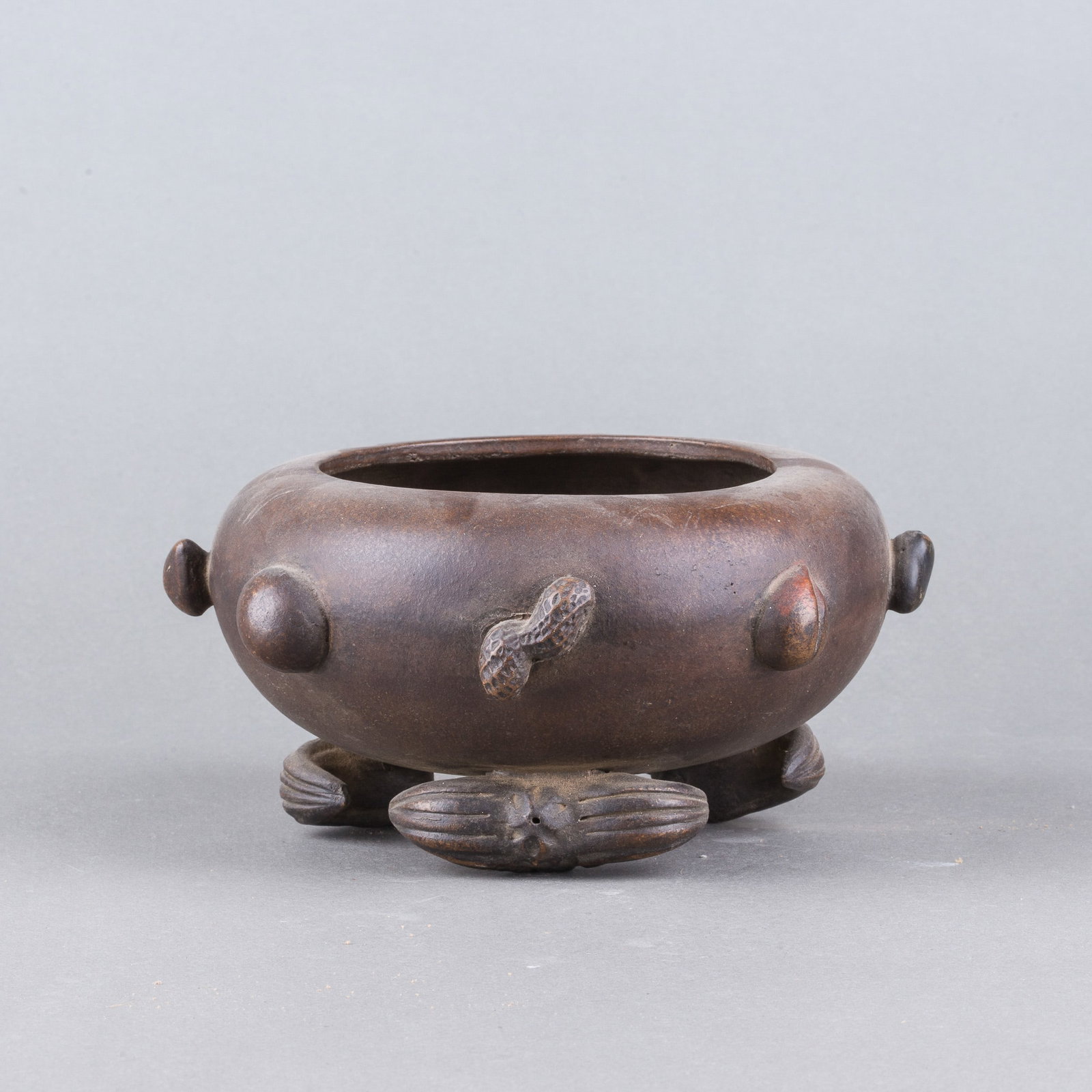 A CHINESE ZISHA TRIPOD CENSER: A Chinese Zisha tripod censer of compressed rounded form, decorated with carved peanut and water chestnut motifs. H10 x 19 cm
