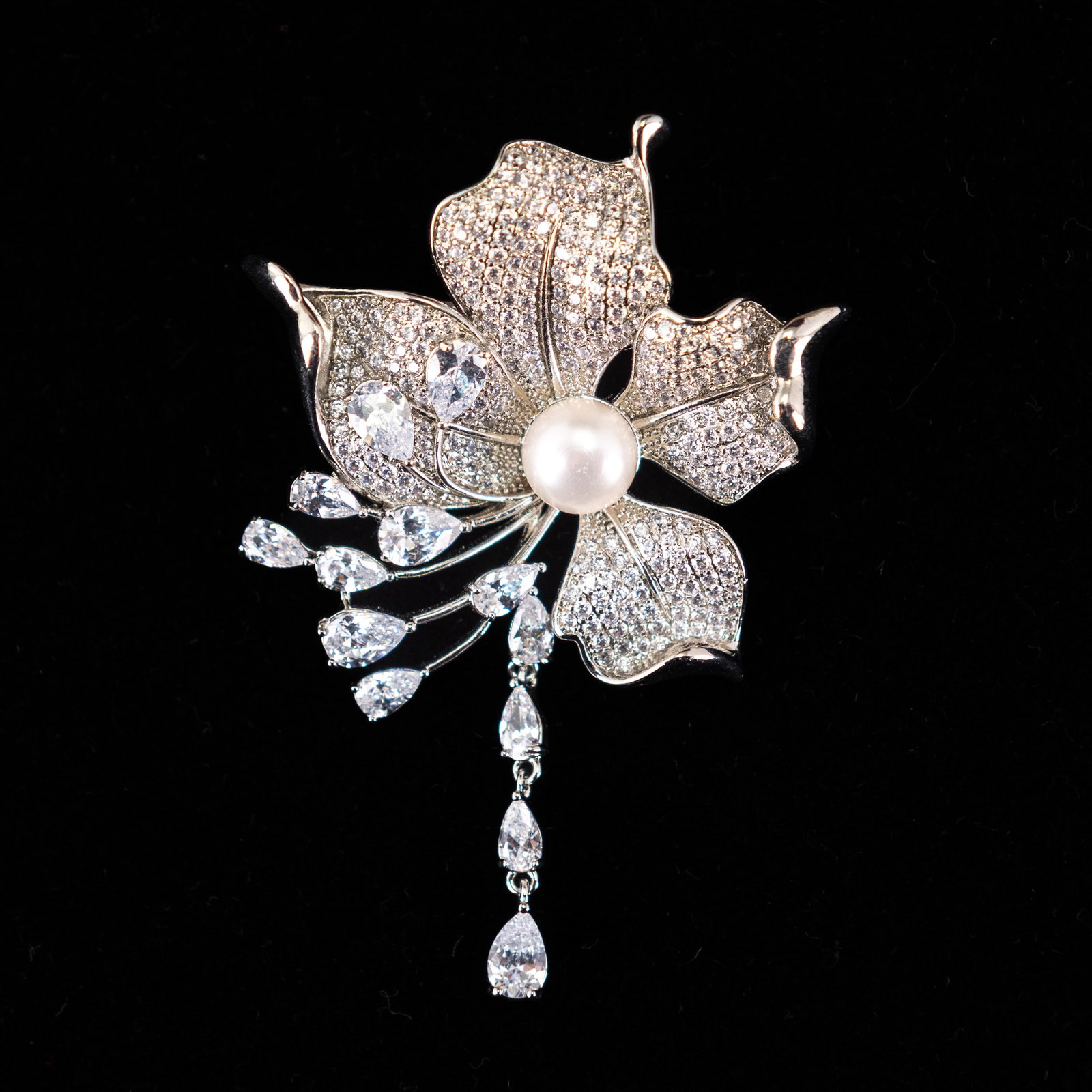 FASHION JEWELRY PEARL BROOCH: Fashion jewelry brooch in a floral shape with diamond-style decoration and a pearl at the center. 1.57"h x 1.97"w (4 x 5 cm)