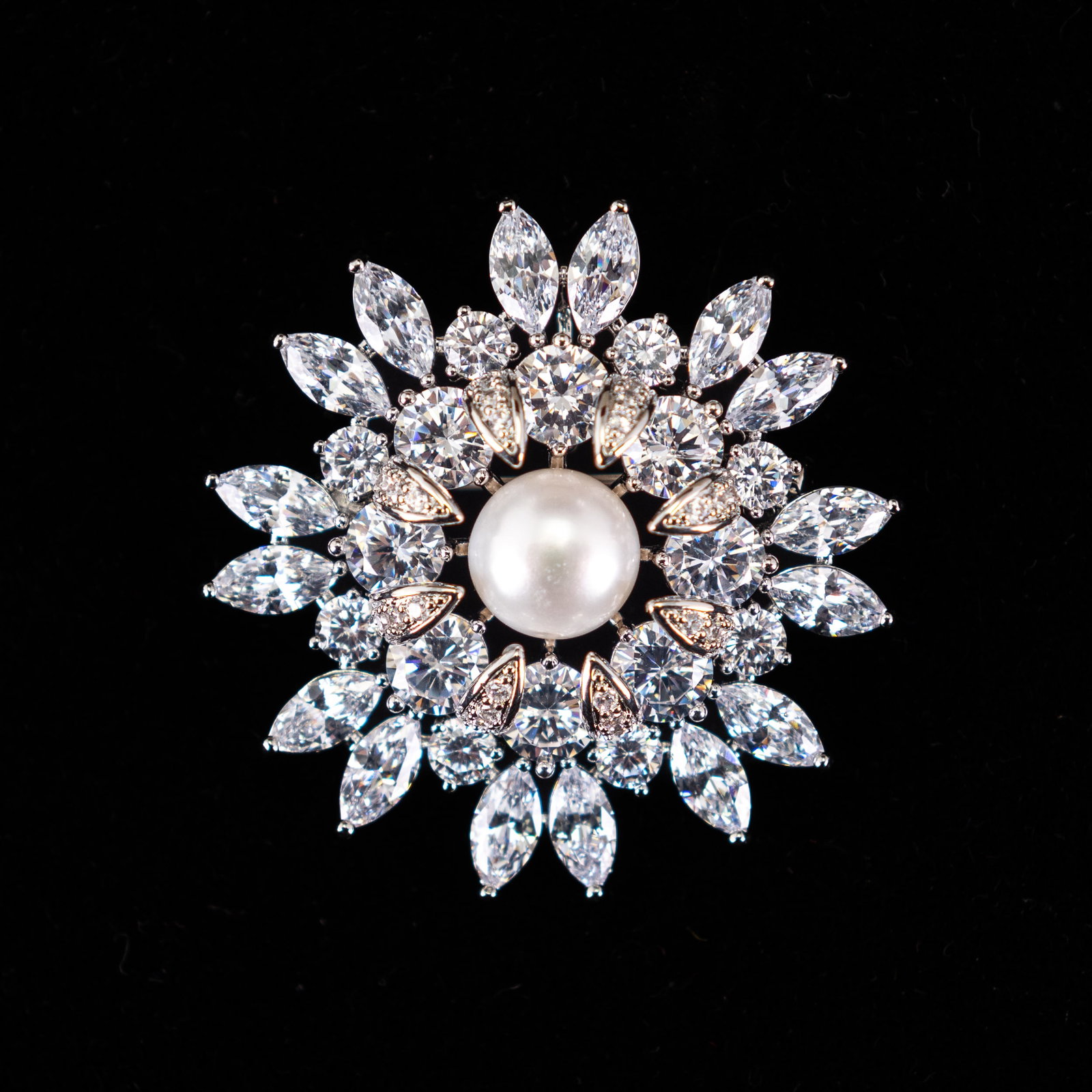 FASHION JEWELRY PEARL BROOCH: Fashion jewelry brooch in a floral shape with diamond-style decoration and a pearl at the center. 1.77"h x 1.97"w (4.5 x 5 cm)