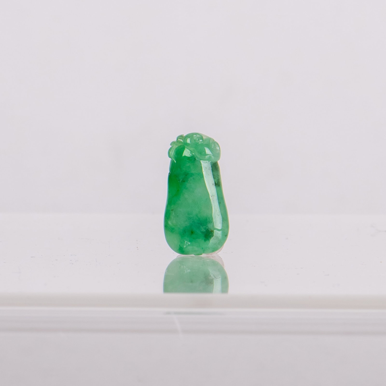 A JADEITE PENDANT: A jadeite pendant, the stone of a pale and spinach-green tone. 1"h x 0.2"w x 0.5"l (2.54 x 0.51 x 1.27 cm)