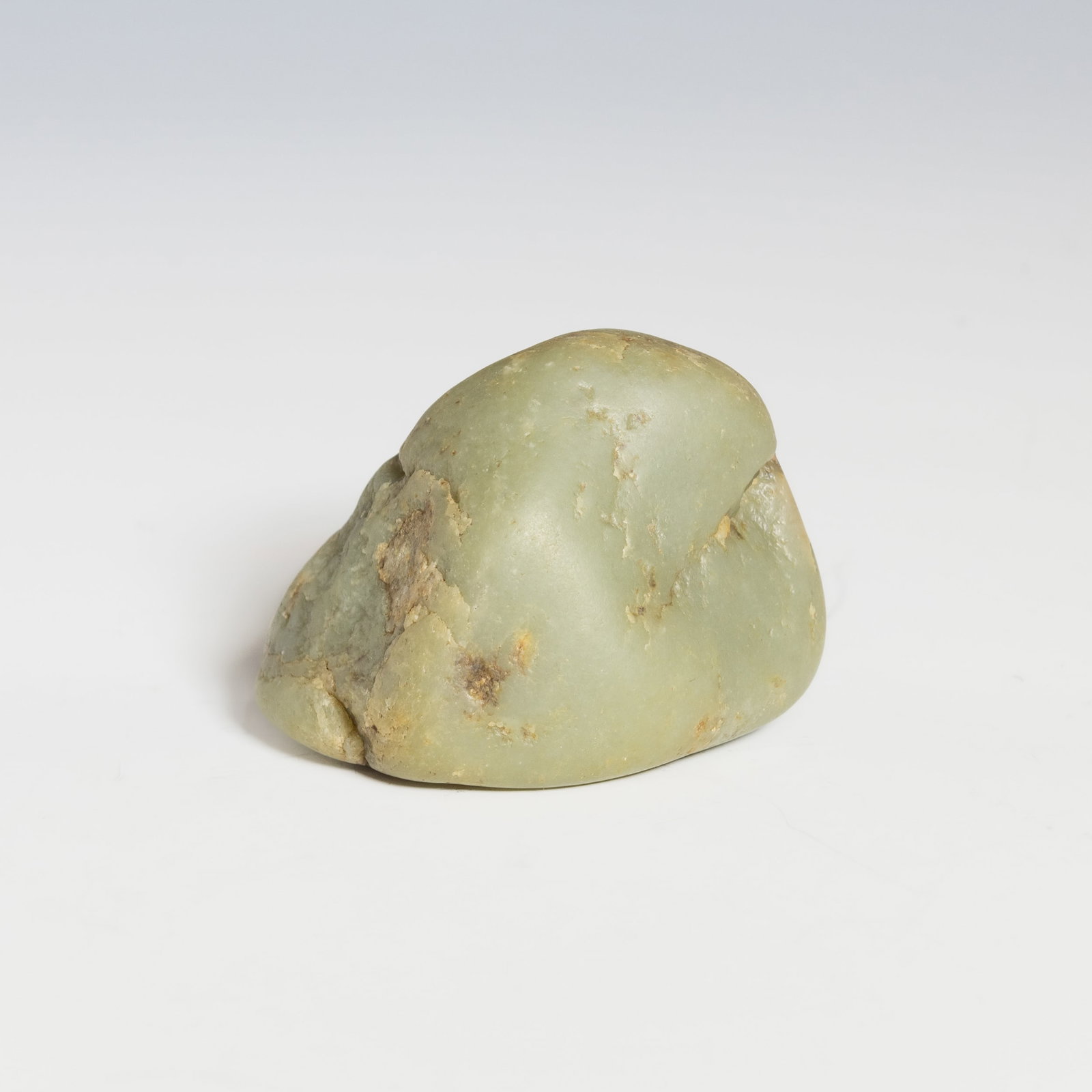HETIAN JADE PEBBLE: A Hetian jade pebble in natural, uncarved form with a smooth surface and warm tone. 2.95"h x 3.94"w x 2.76"l (7.5 x 10 x 7 cm); Weight: 694 g