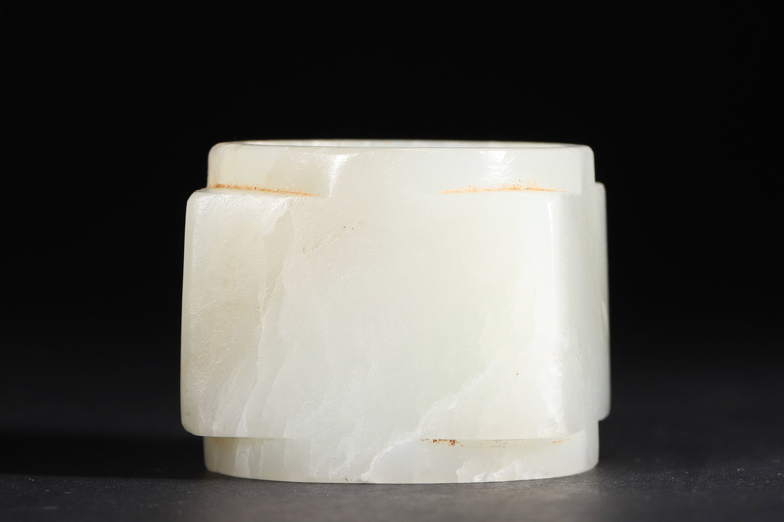A WHITE JADE CONG-FORM THUMB RING: A white jade thumb ring of cong form, with a square exterior and circular interior. L. 5 cm; W. 5 cm; Ht. 4.2 cm; Wt. 121 g.