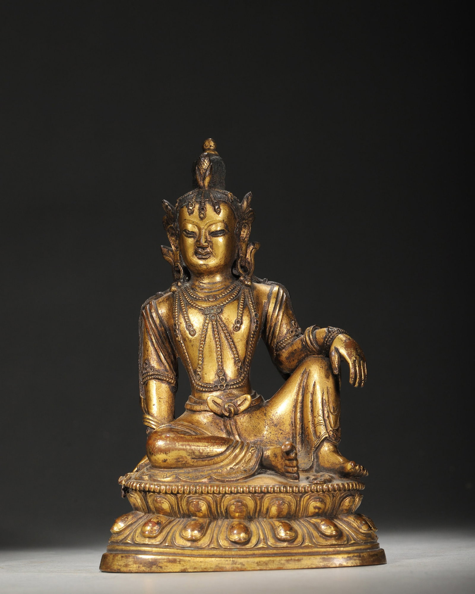 A GILT-BRONZE FIGURE OF GUANYIN: A gilt-bronze figure of Guanyin seated on a lotus base. L. 11 cm; Ht. 16.6 cm; Wt. 1,332 g.