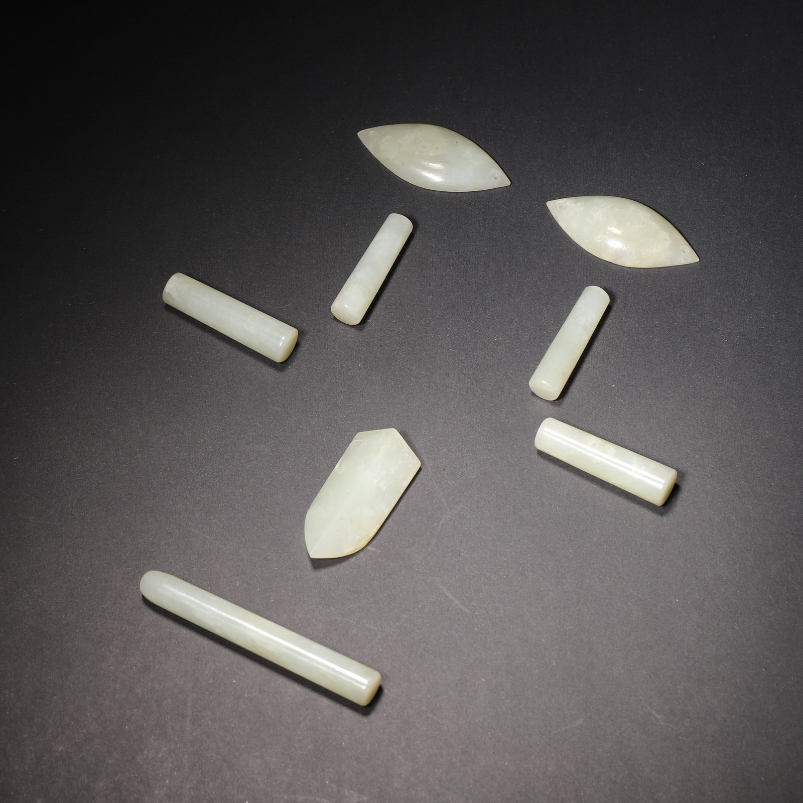 A SET OF EIGHT PALE GREENISH-WHITE JADE NINE-ORIFICE BURIAL PIECES: A set of eight pale greenish-white jade nine-orifice burial pieces. L. 7 cm; Wt. 78.37 g.