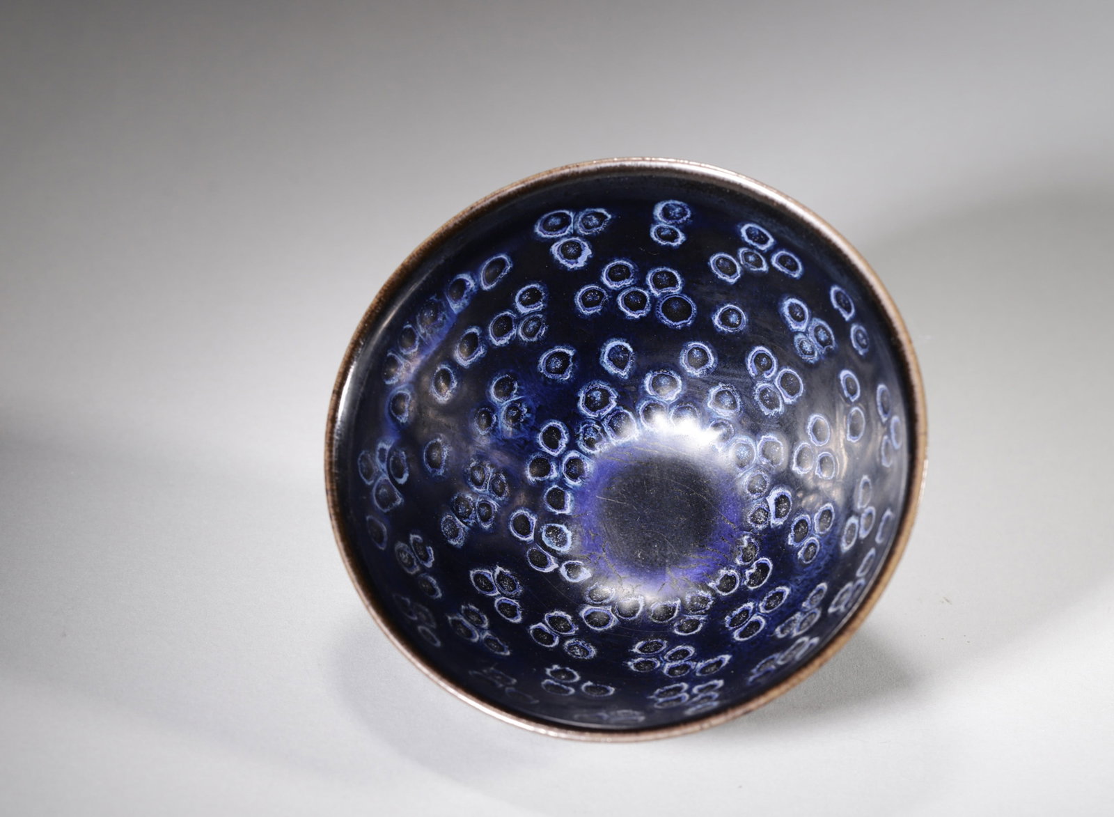 A BLACK-GLAZED 'YAO BIAN' JIAN-STYLE TEA BOWL: A black-glazed Jian-style tea bowl with blue 'yao bian' spots. The base bears a mark reading 'Gongyu'. Diam. 13.6 cm; Ht. 7.5 cm. Note: By repute, a type associated with tea competition.