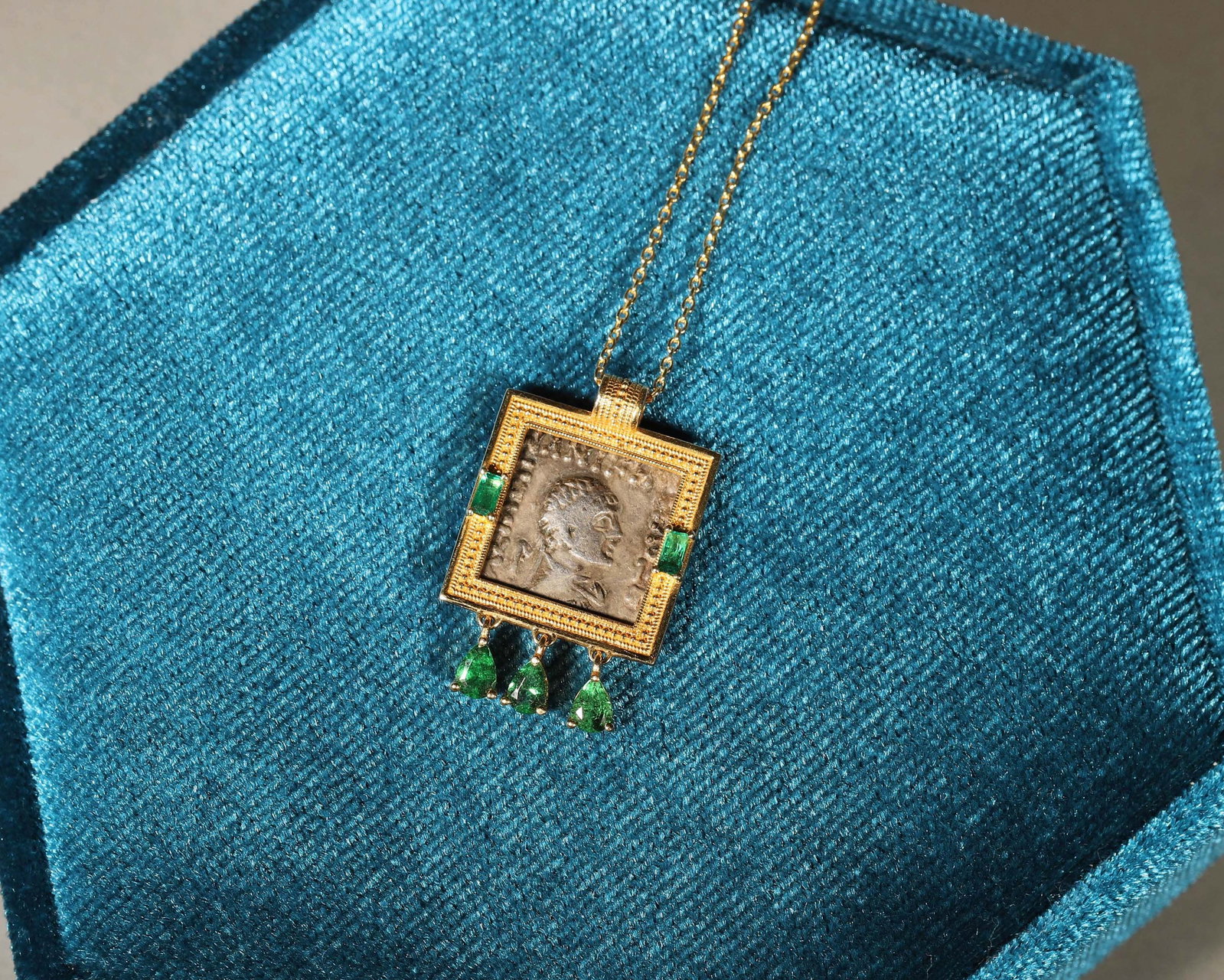 AN 18K GOLD AND TSAVORITE PENDANT WITH 925 SILVER CHAIN: An 18K gold pendant set with tsavorite, with a 925 silver chain. W. 1.8 cm; Wt. 5 g.
